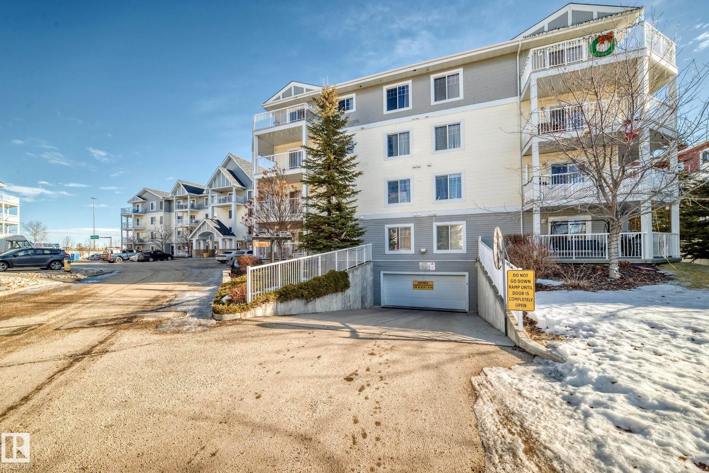 The property features a multi-story building with a light-colored facade and dark trim details, including several balconies - 208 2204 44 Ave, Edmonton, AB - Outdoor With Facade