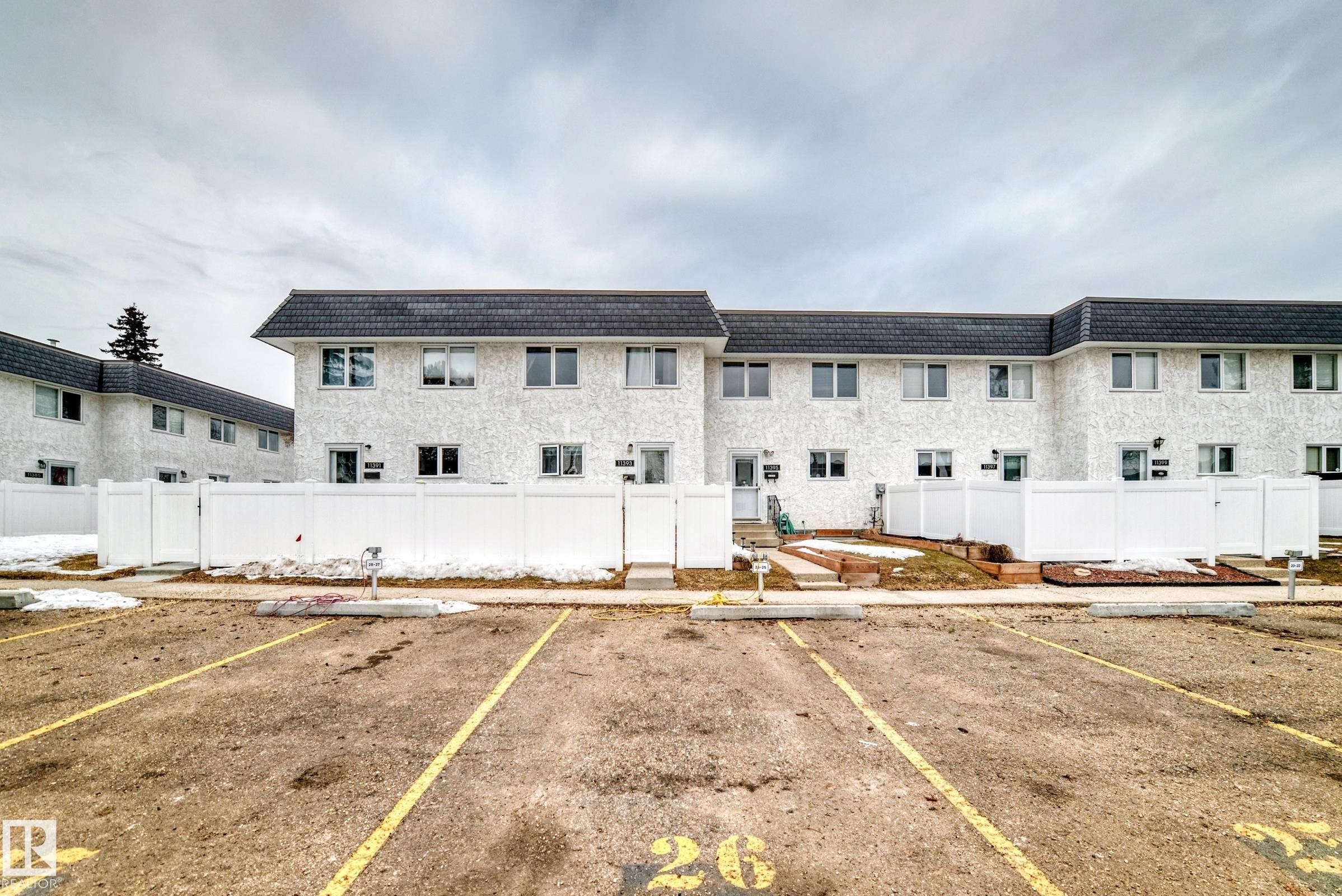 The property features a multi-unit building with a white exterior finish and dark sloped roofs - 11393 22 Avenue, Edmonton, AB - Outdoor
