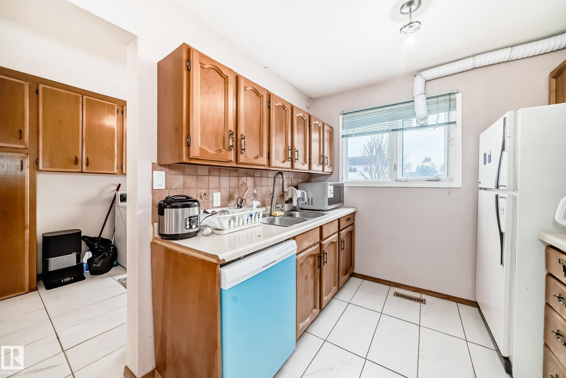 Kitchen featuring wood cabinetry, white tiled flooring, a window providing natural light, and a white refrigerator - 11393 22 Avenue, Edmonton, AB - Indoor Photo Showing Kitchen