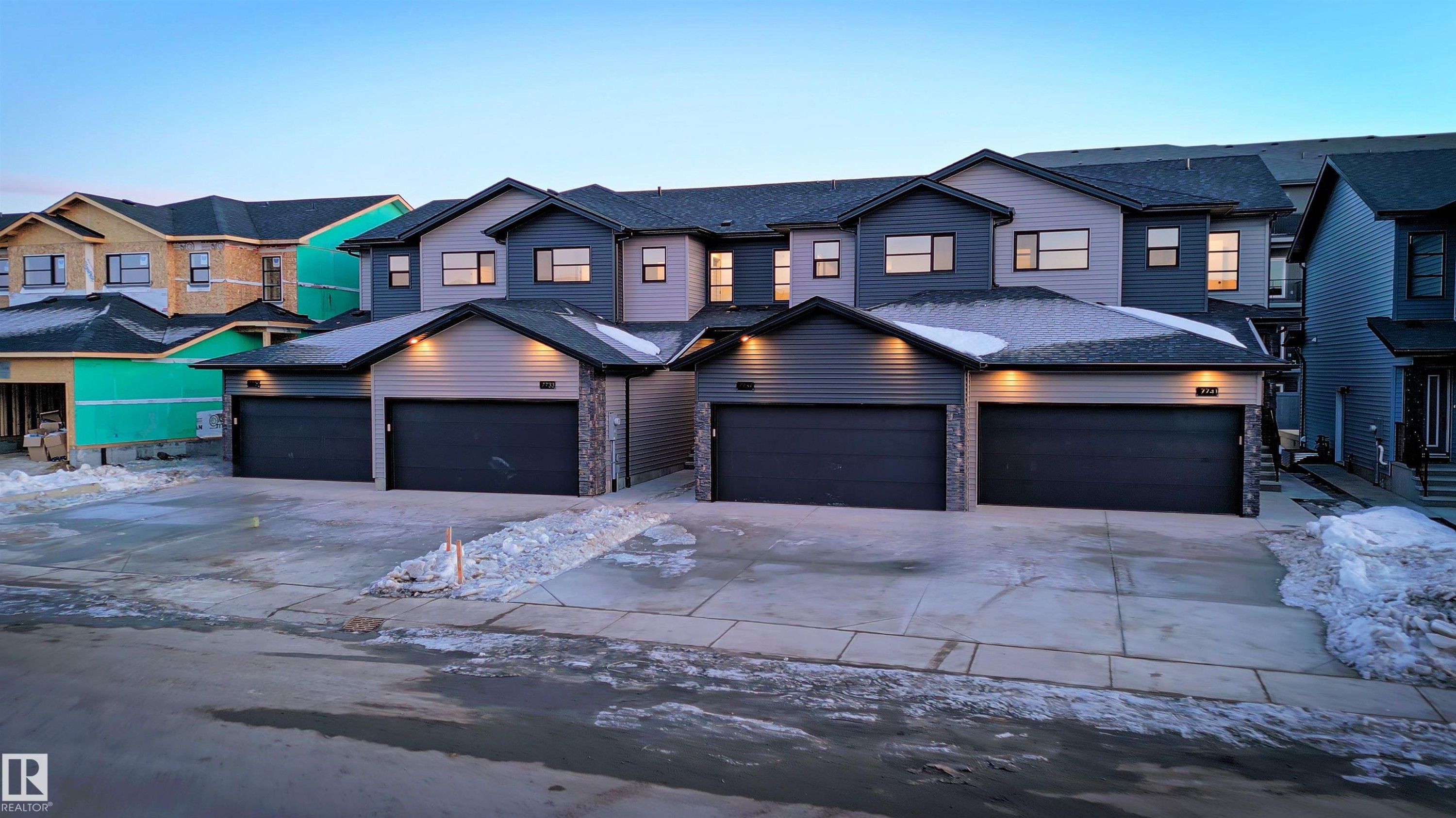 The property features a contemporary exterior with grey siding and dark trim, accented by stone pillars - 7694 174A Avenue, Edmonton, AB - Outdoor With Facade