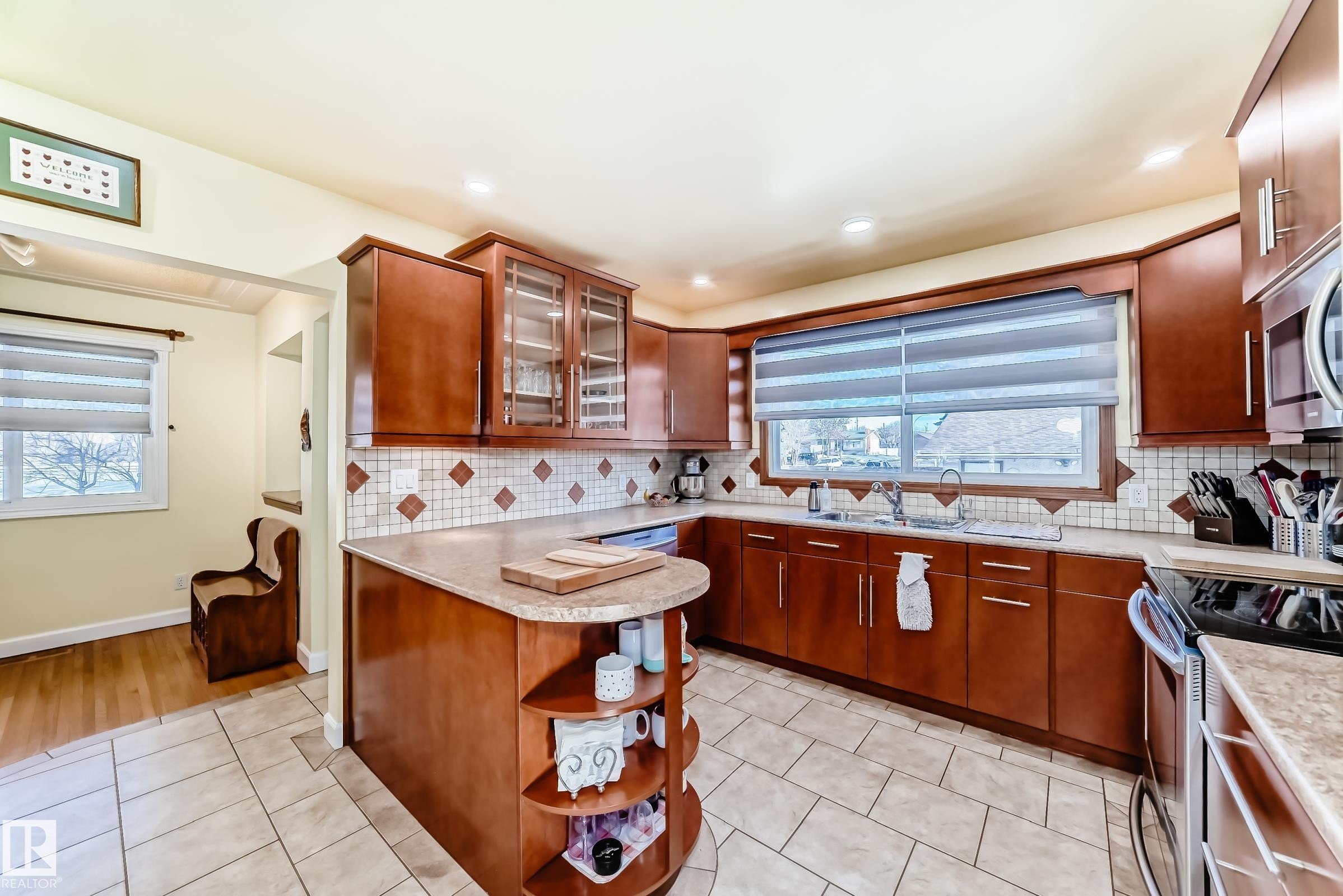 Well-appointed kitchen featuring wood cabinetry, a tiled backsplash, and a large window above the sink - 4446 116 Avenue, Edmonton, AB - Indoor Photo Showing Kitchen With Double Sink