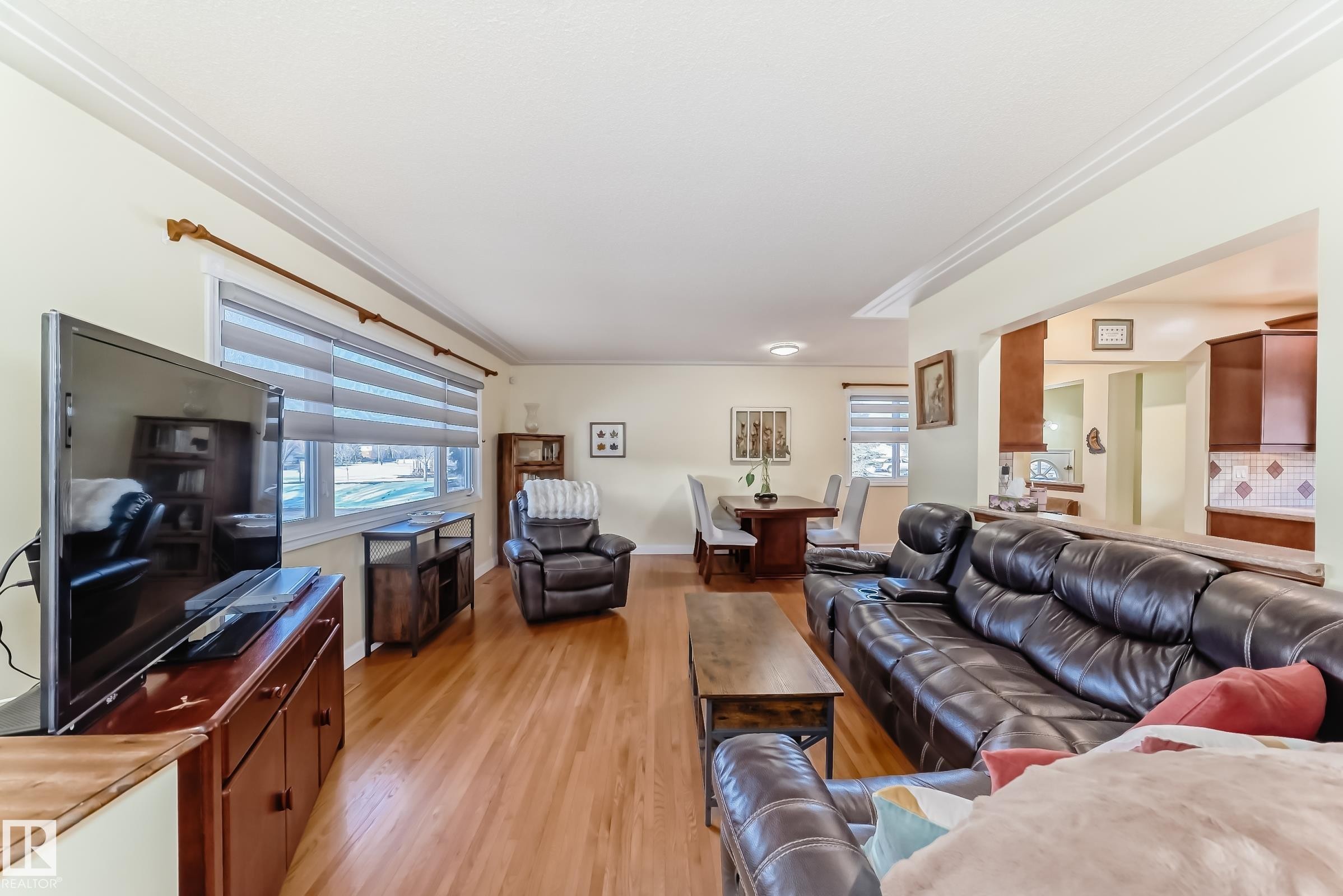Living area featuring hardwood floors, crown molding, and large windows providing natural light - 4446 116 Avenue, Edmonton, AB - Indoor Photo Showing Living Room