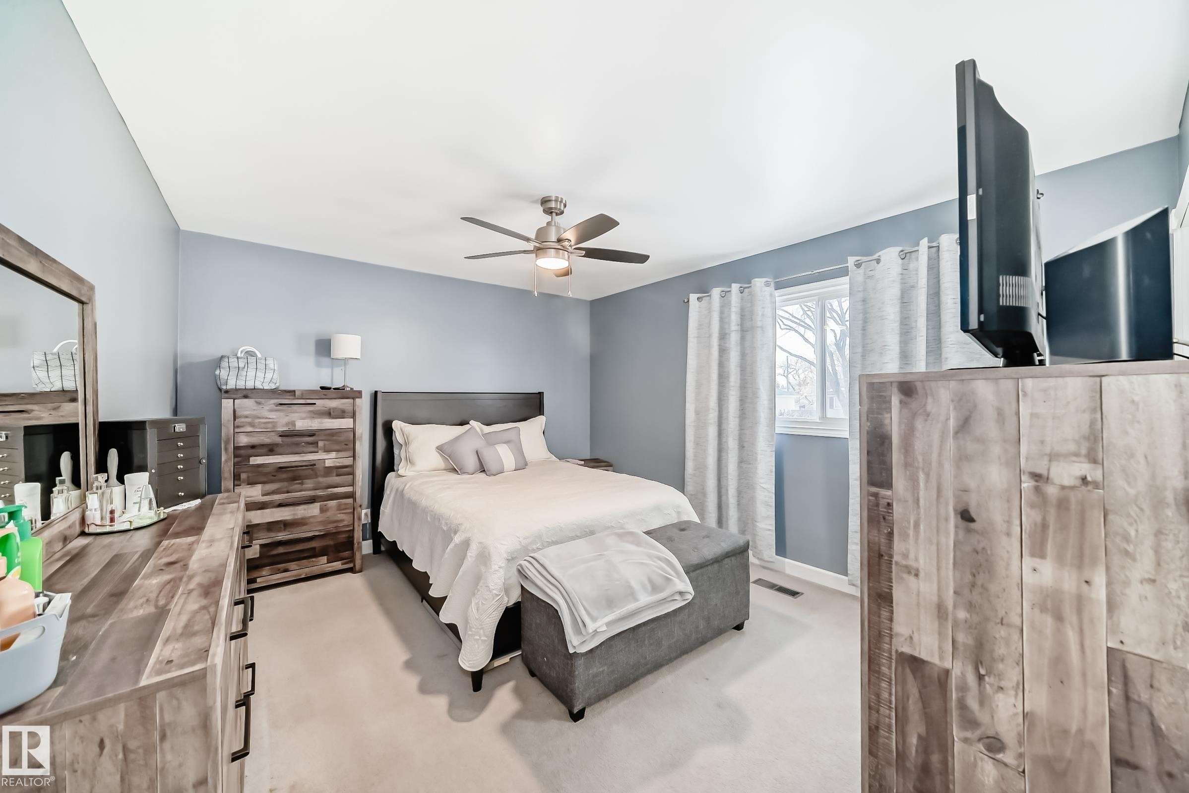 Spacious room featuring light blue walls, a ceiling fan, and a window with curtains - 4446 116 Avenue, Edmonton, AB - Indoor Photo Showing Bedroom