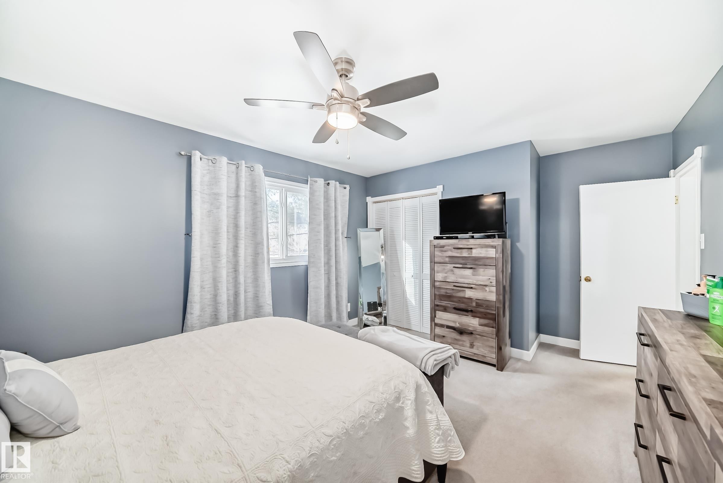 This room features carpeted flooring, a ceiling fan with integrated lighting, and a window providing natural light - 4446 116 Avenue, Edmonton, AB - Indoor Photo Showing Bedroom