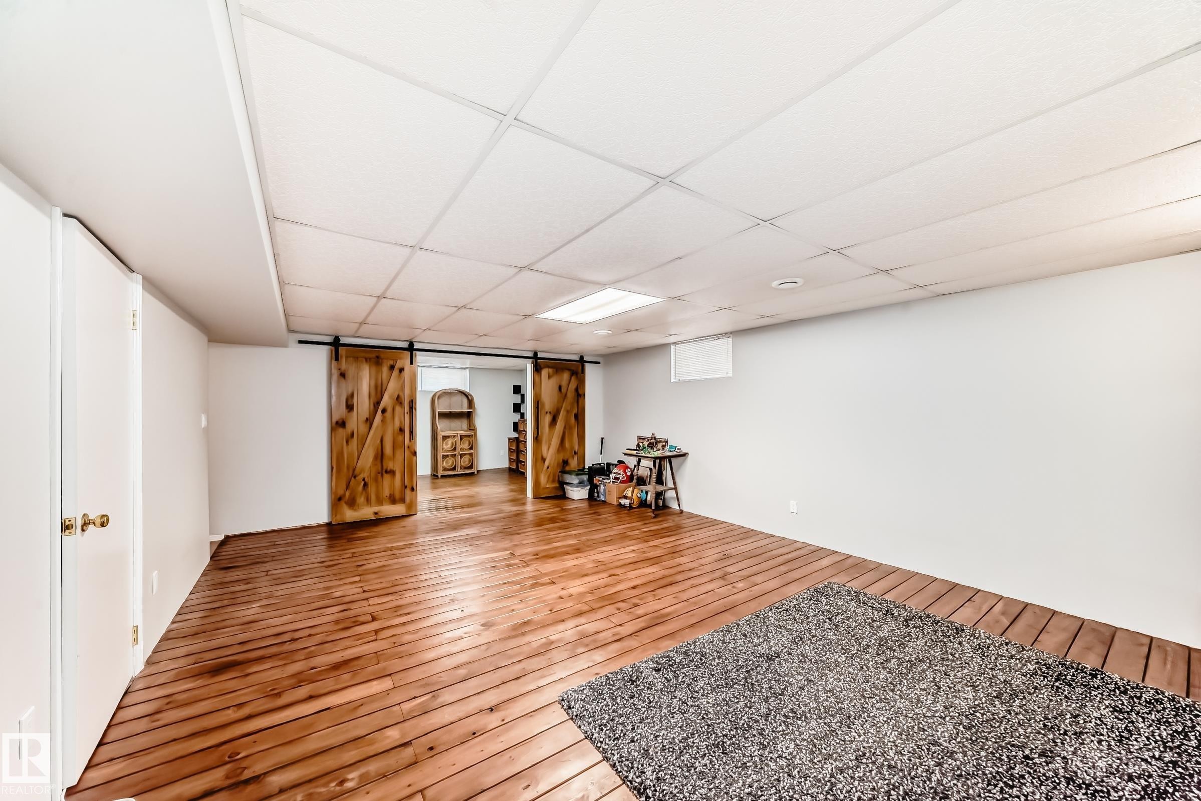 The property features durable wood flooring and spacious walls, creating an open and versatile interior - 4446 116 Avenue, Edmonton, AB - Indoor