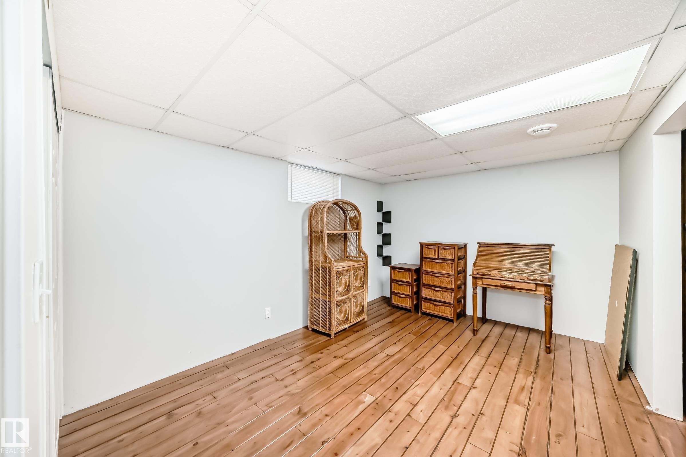 This versatile room features warm wood flooring and a drop ceiling with recessed lighting, offering a blank canvas for customization - 4446 116 Avenue, Edmonton, AB - Indoor Photo Showing Other Room
