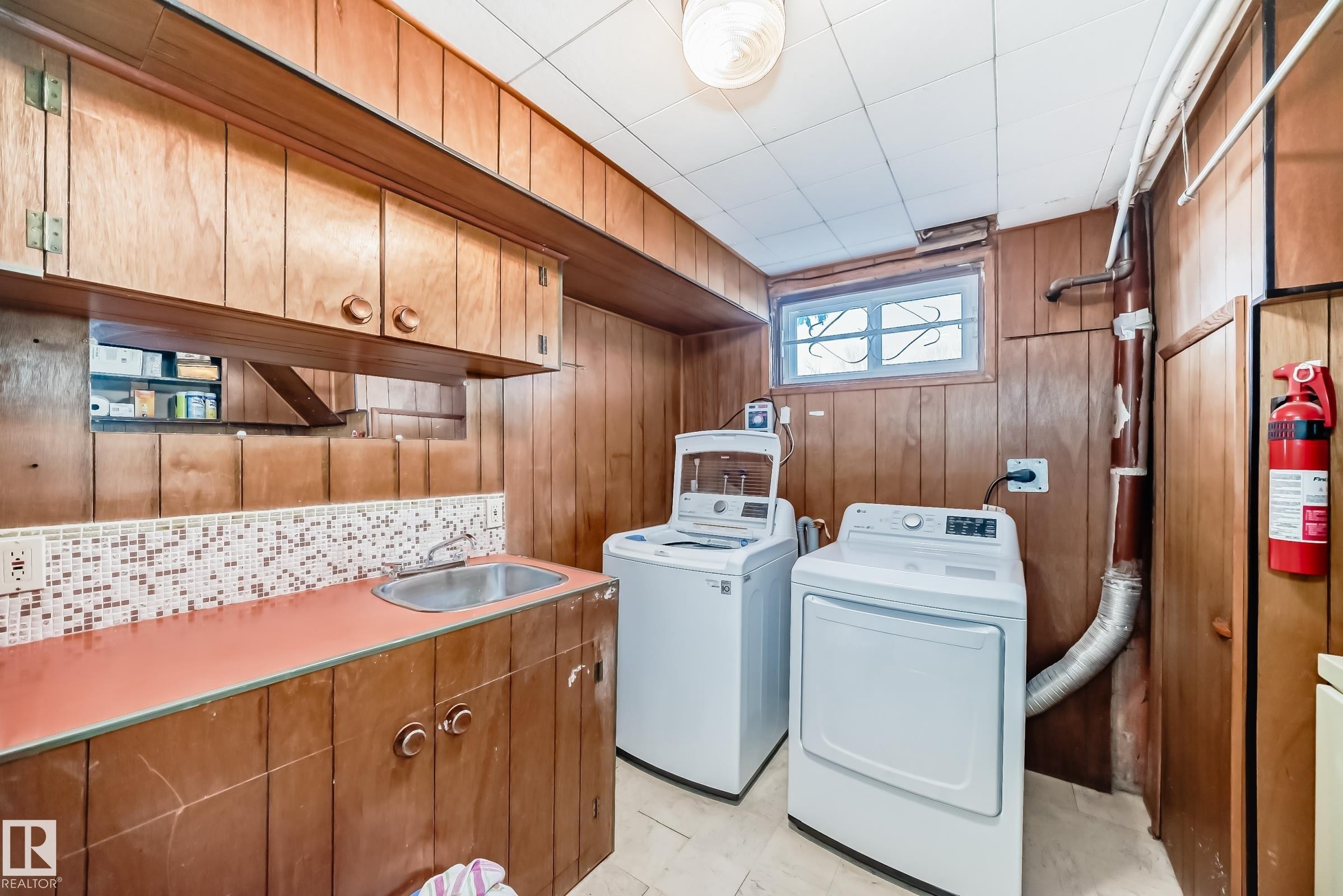 The utility area features wood paneling, a window, and a sink with cabinetry - 4446 116 Avenue, Edmonton, AB - Indoor Photo Showing Laundry Room