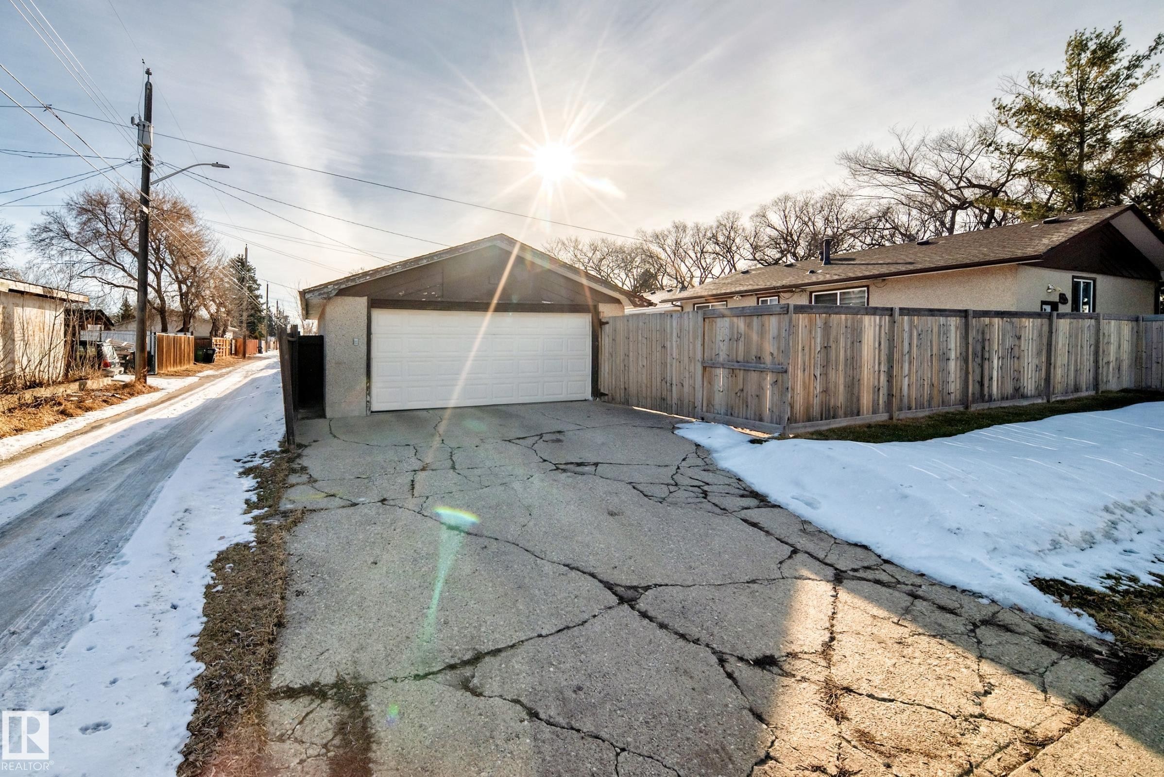 The property features a detached garage with a white garage door, and a private wooden fence - 4446 116 Avenue, Edmonton, AB - Outdoor
