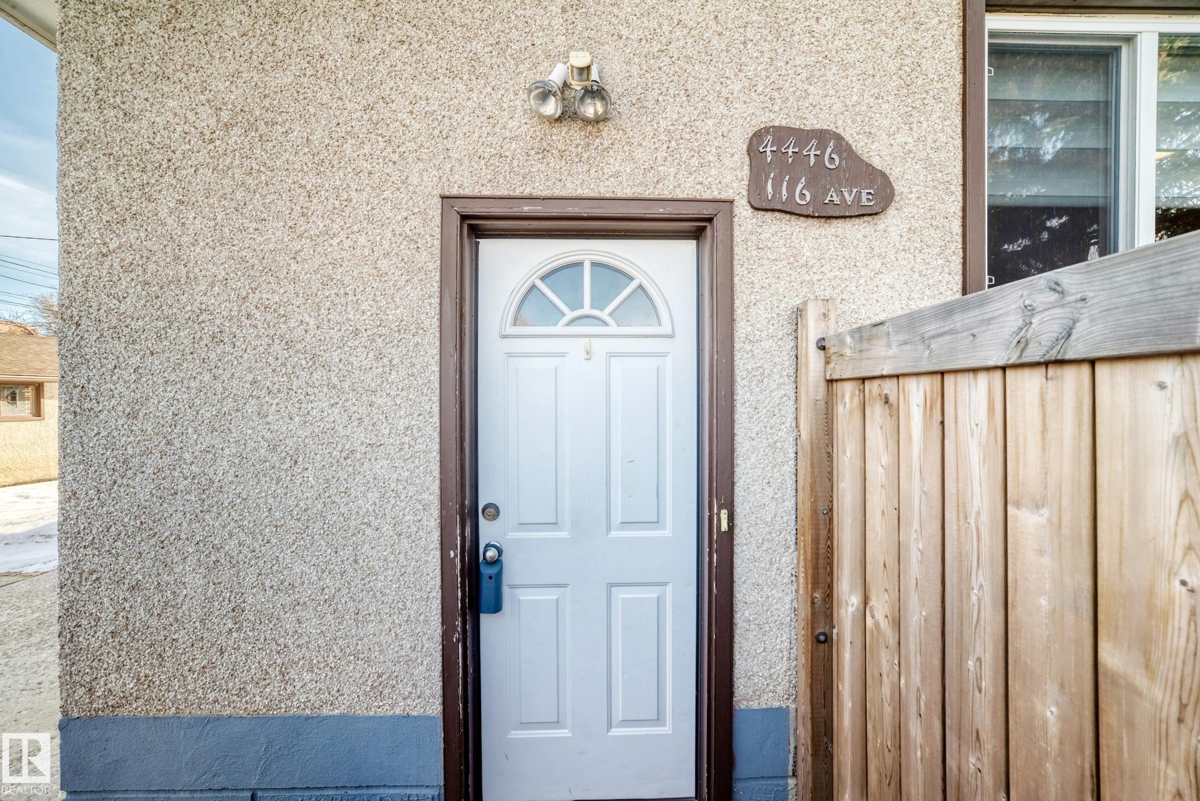 The property features a white exterior door with a decorative transom window, set within a brown frame - 4446 116 Avenue, Edmonton, AB - Outdoor With Exterior