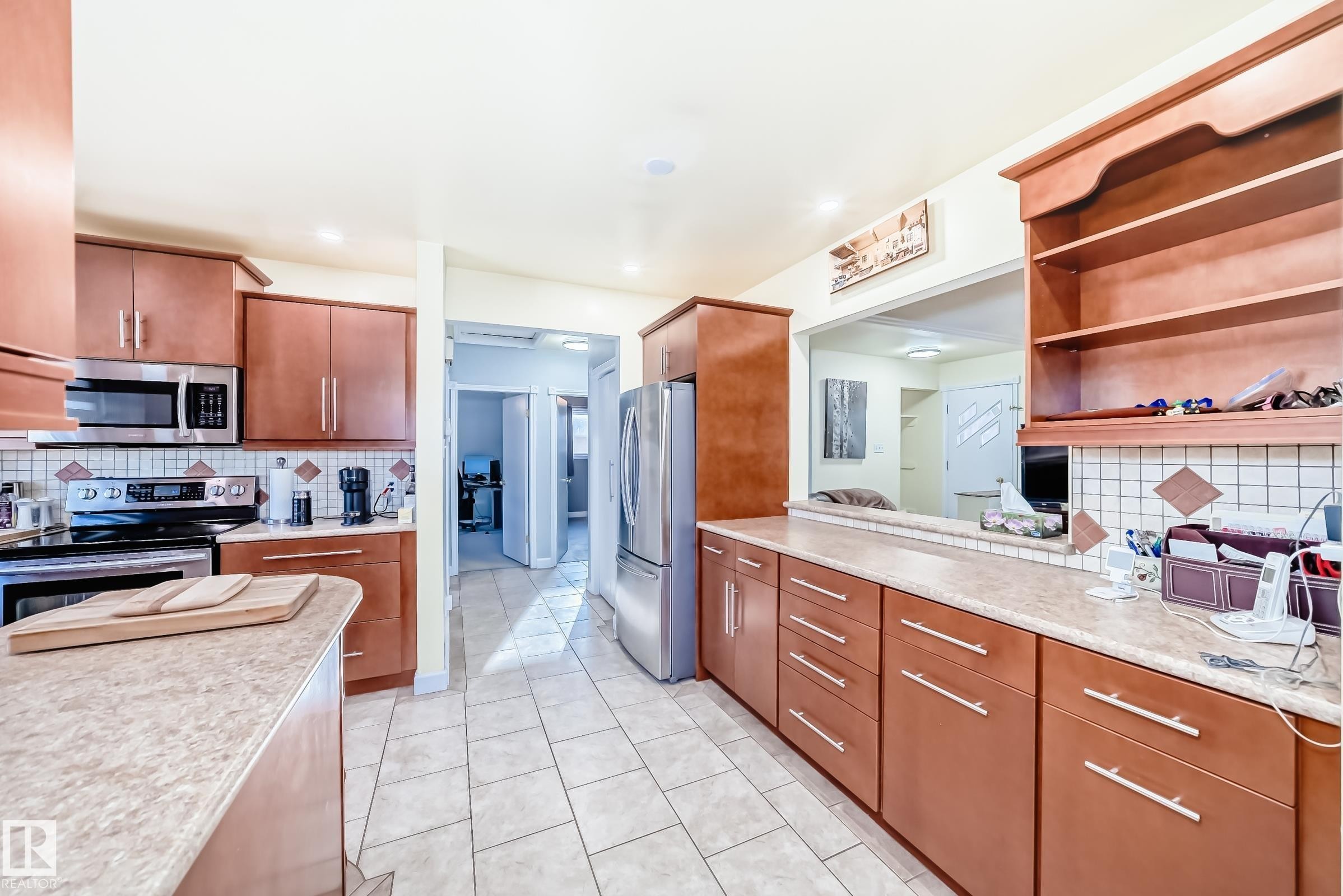 The kitchen features extensive cabinetry, light-colored countertops, and stainless steel appliances - 4446 116 Avenue, Edmonton, AB - Indoor Photo Showing Kitchen