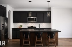 The kitchen features a dark wood island with a dark countertop and three bar stools -
