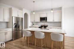 The kitchen features stainless steel appliances, including a microwave, refrigerator, and range -