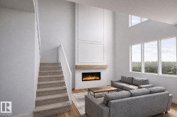 The living area features a high ceiling, an electric fireplace with a wooden mantel, and large windows offering views of lush greenery -