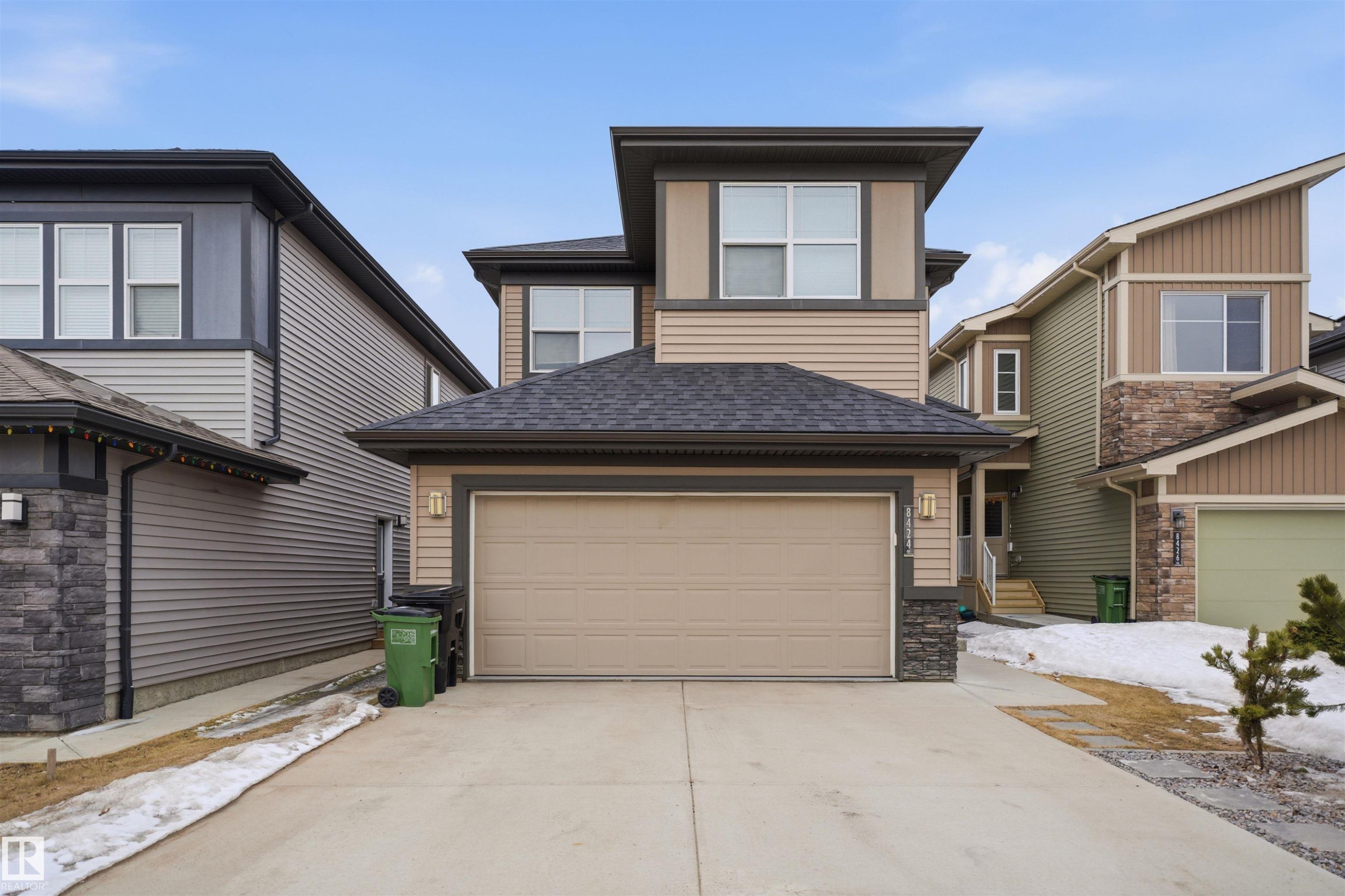 The property features a two-story design with a prominent beige garage door and a dark shingled roof - 8424 Cushing Court, Edmonton, AB - Outdoor