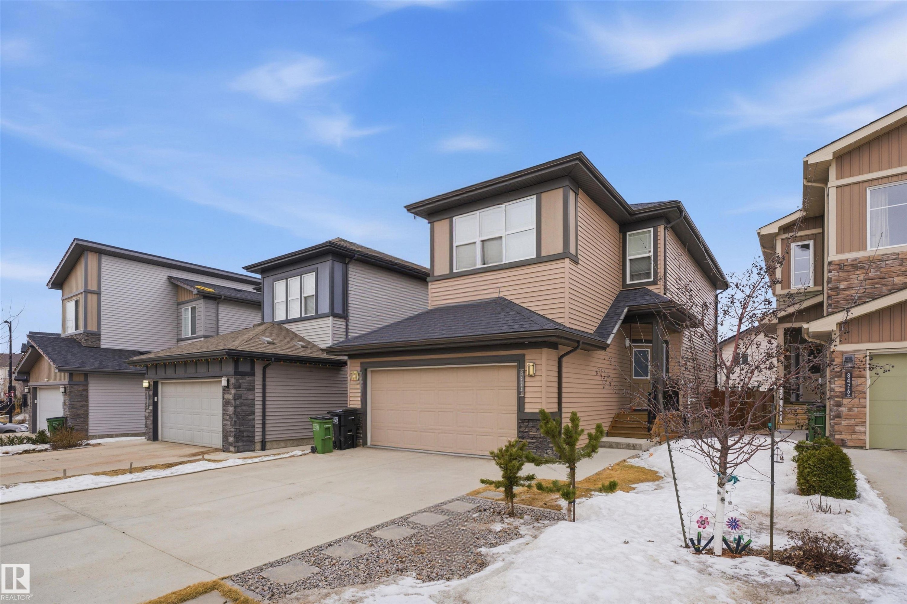 The property features an exterior with light brown siding, a dark roof, and an attached garage with a light brown door - 8424 Cushing Court, Edmonton, AB - Outdoor With Facade