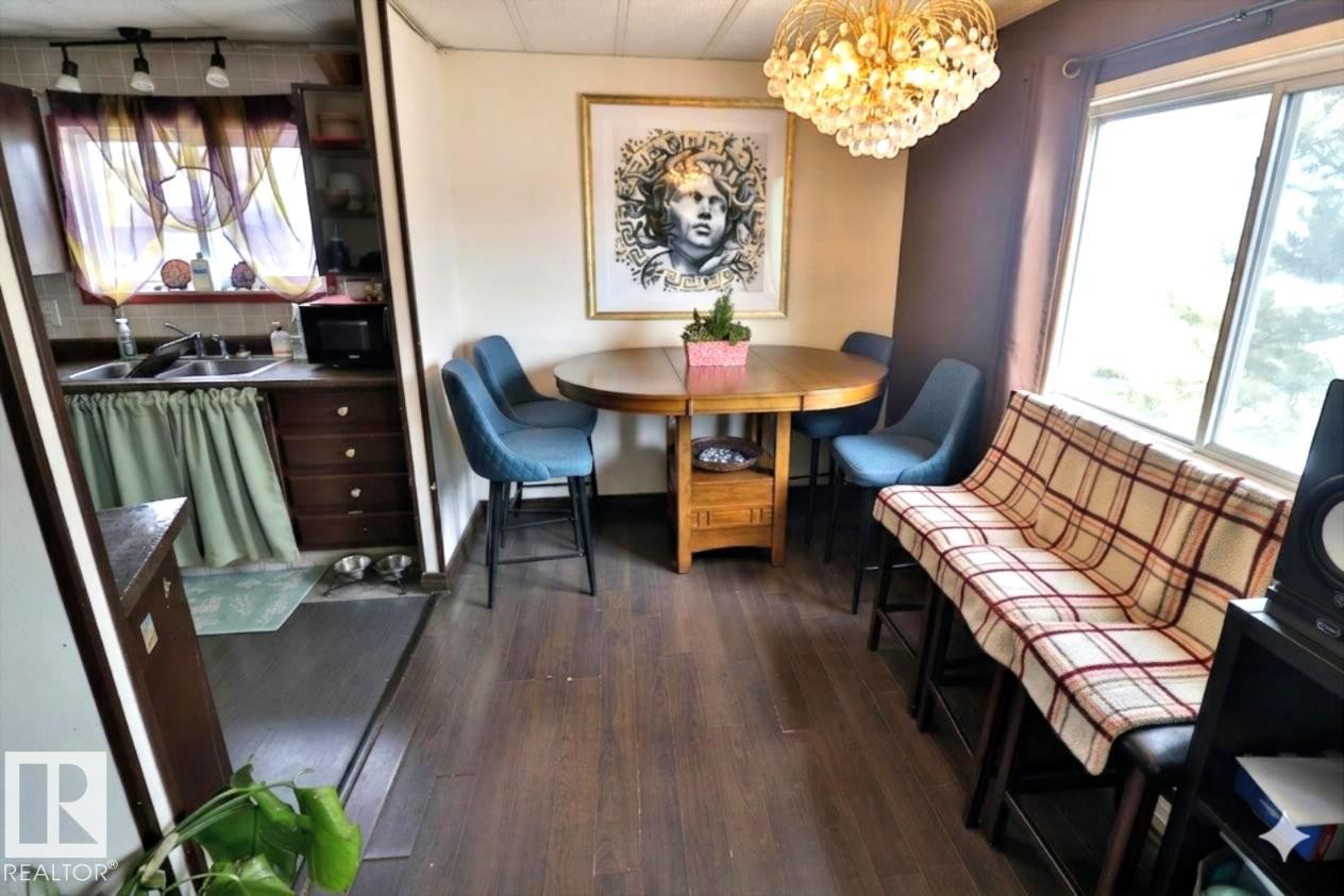 This dining area features hardwood style flooring, a window, and a decorative light fixture - 11 Willow Park Estates, Leduc, AB - Indoor Photo Showing Dining Room
