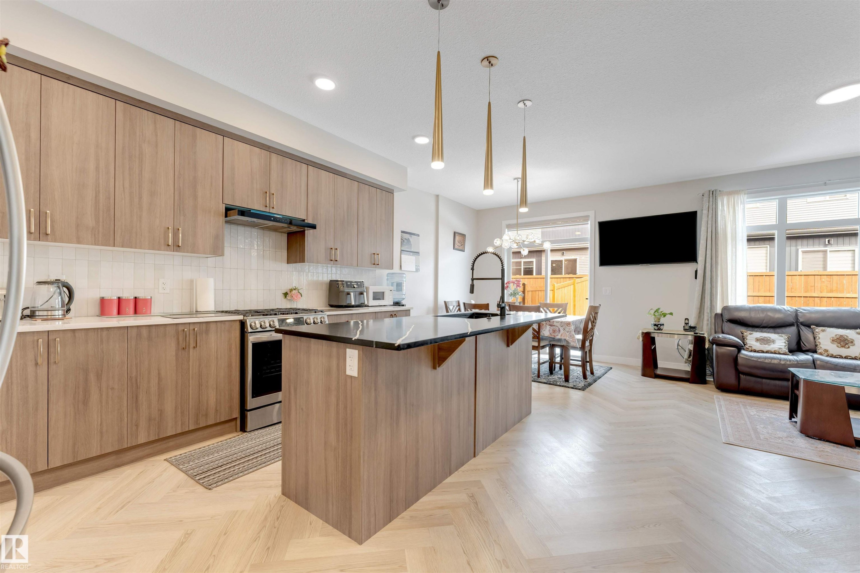 The open-concept main living area features light-toned flooring, a kitchen with cabinetry, and a central island with a dark countertop - 6404 27 Avenue, Edmonton, AB - Indoor Photo Showing Kitchen With Upgraded Kitchen