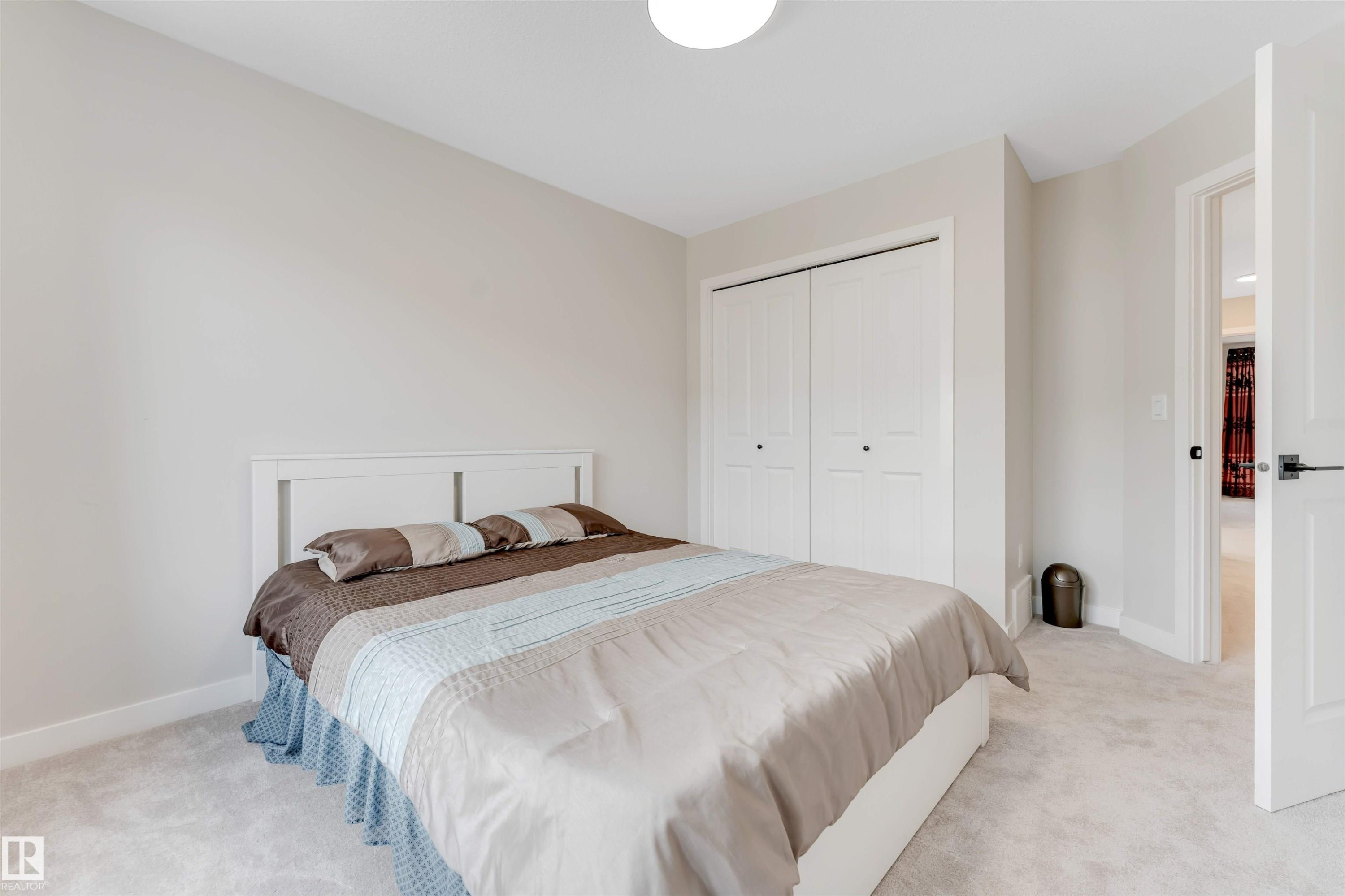 This room features light-colored walls and carpeting, a white paneled closet, and a white paneled door with dark hardware - 6404 27 Avenue, Edmonton, AB - Indoor Photo Showing Bedroom