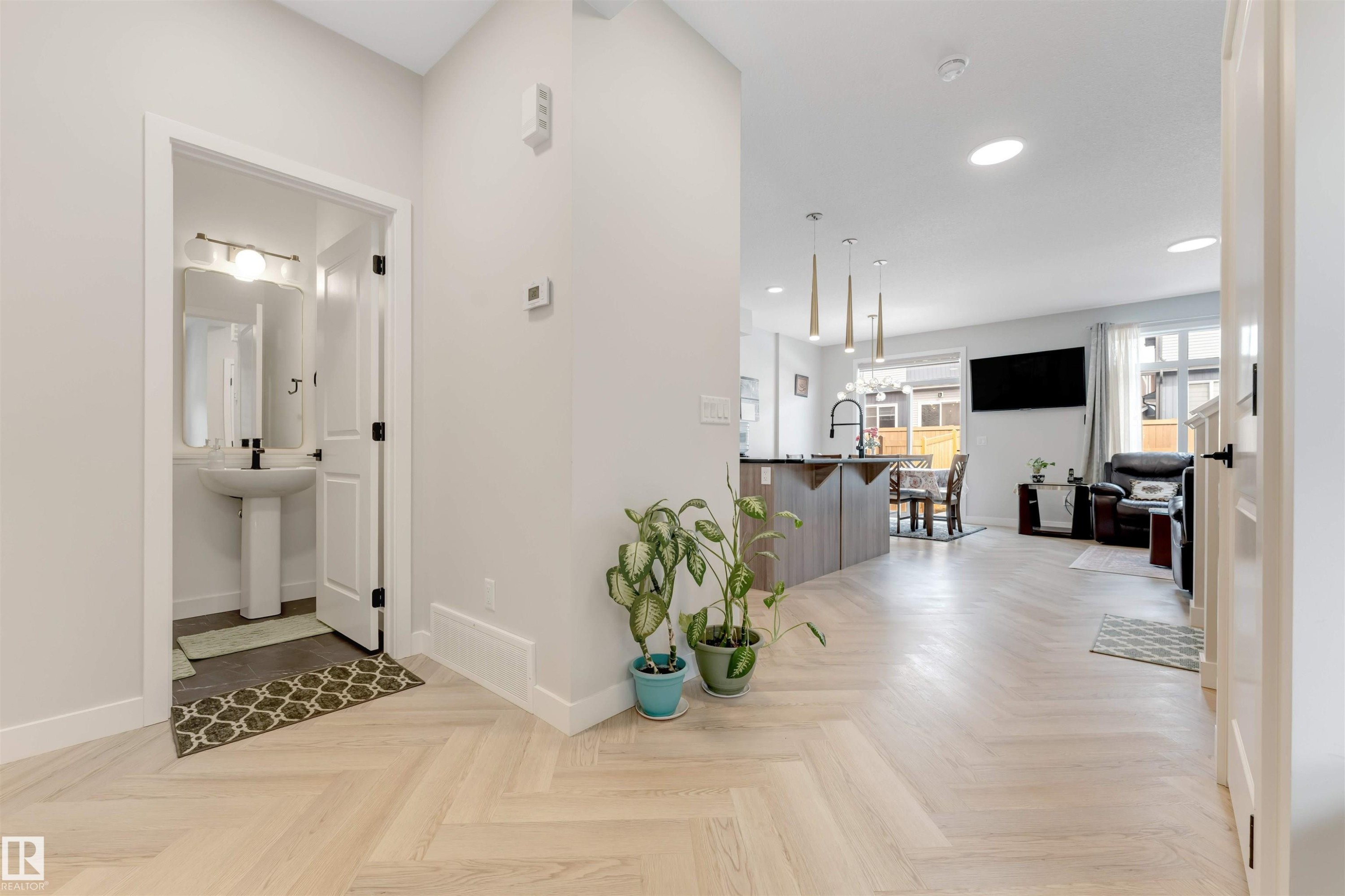 The property features light-toned flooring in a herringbone pattern, leading to an open concept living area - 6404 27 Avenue, Edmonton, AB - Indoor