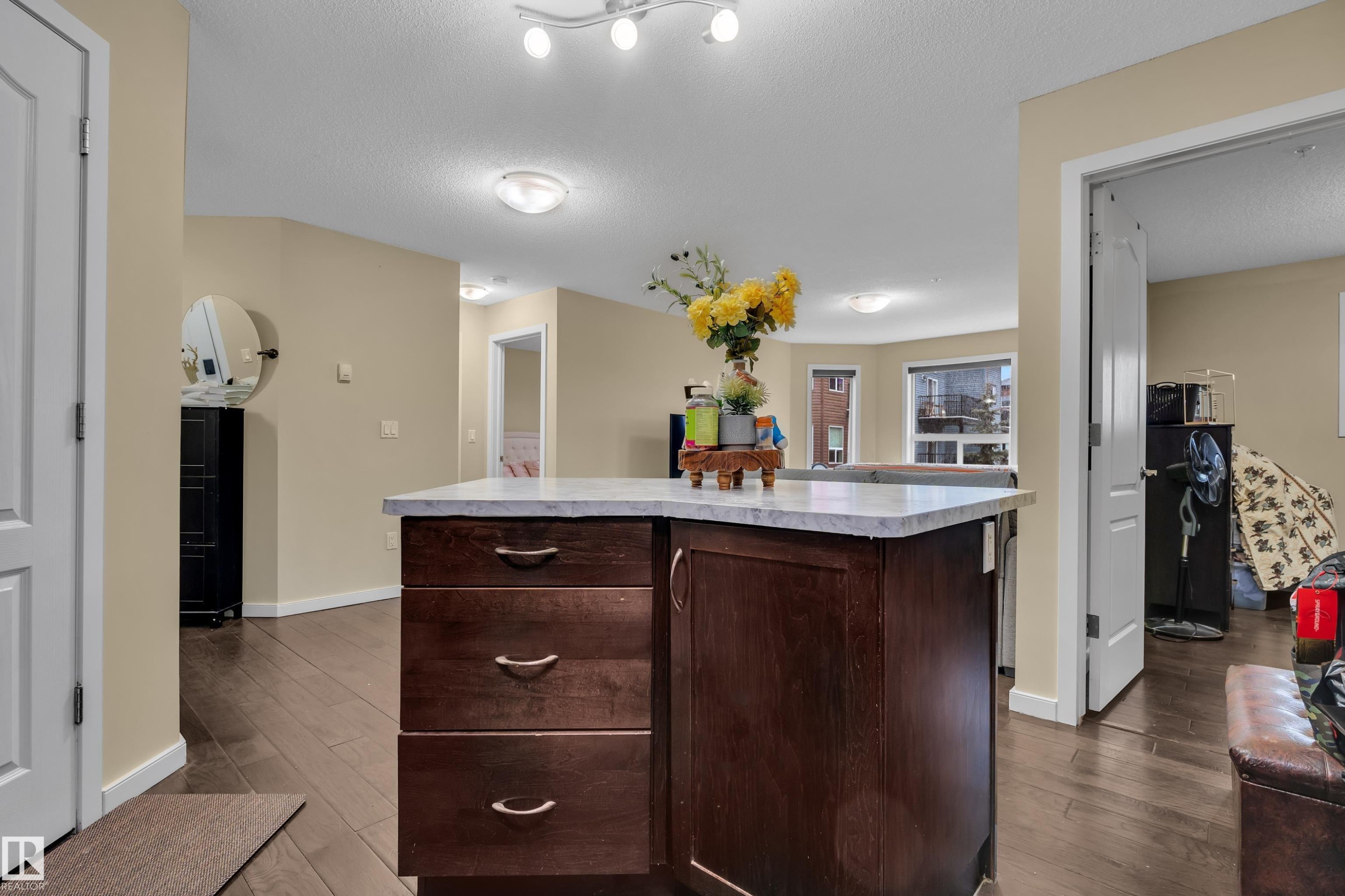 Kitchen island with a light-colored countertop and dark wood cabinetry featuring three drawers - 320 392 Silver Berry Road, Edmonton, AB - Indoor
