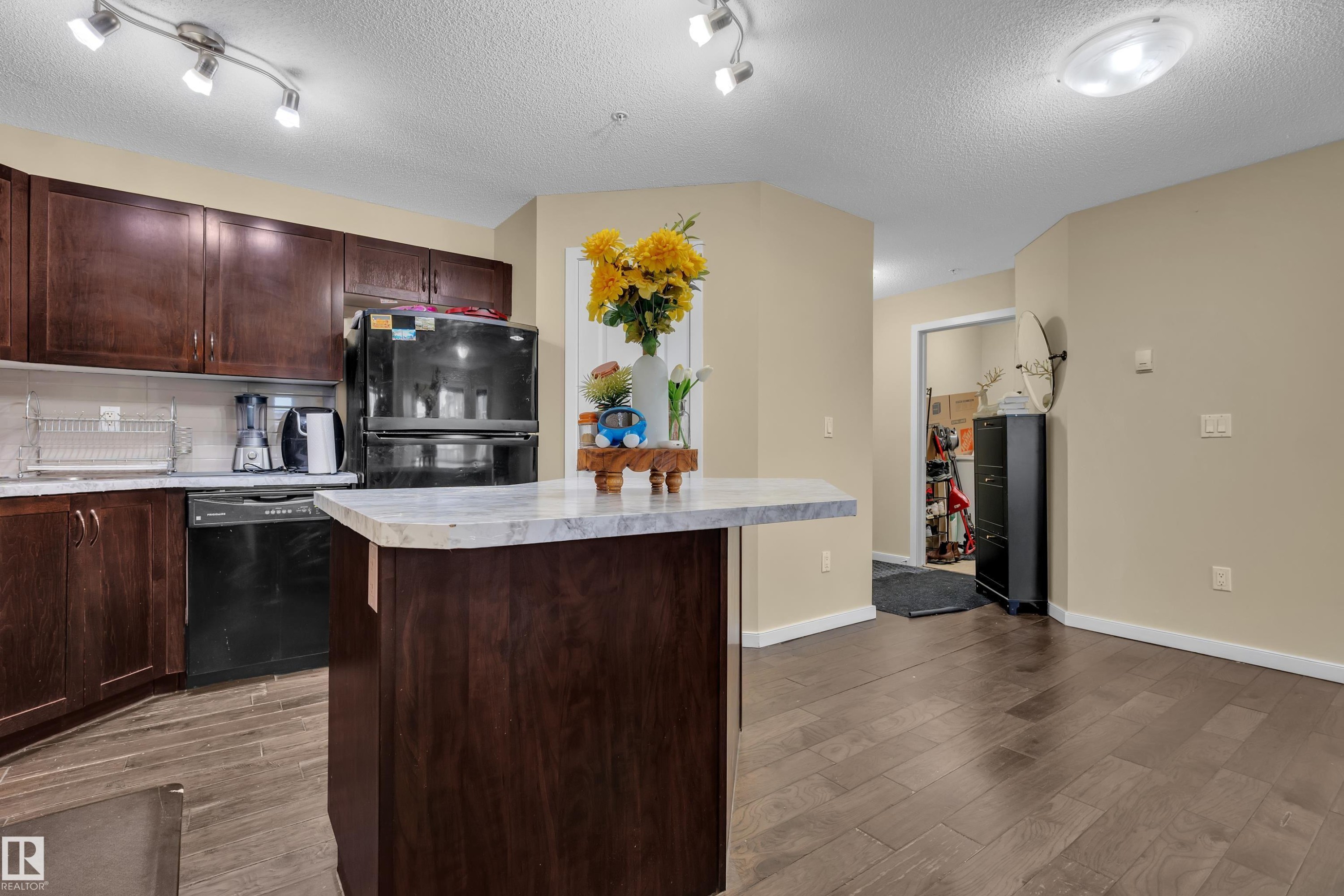 The kitchen features dark wood cabinetry, a dark refrigerator, and a dishwasher - 320 392 Silver Berry Road, Edmonton, AB - Indoor Photo Showing Kitchen