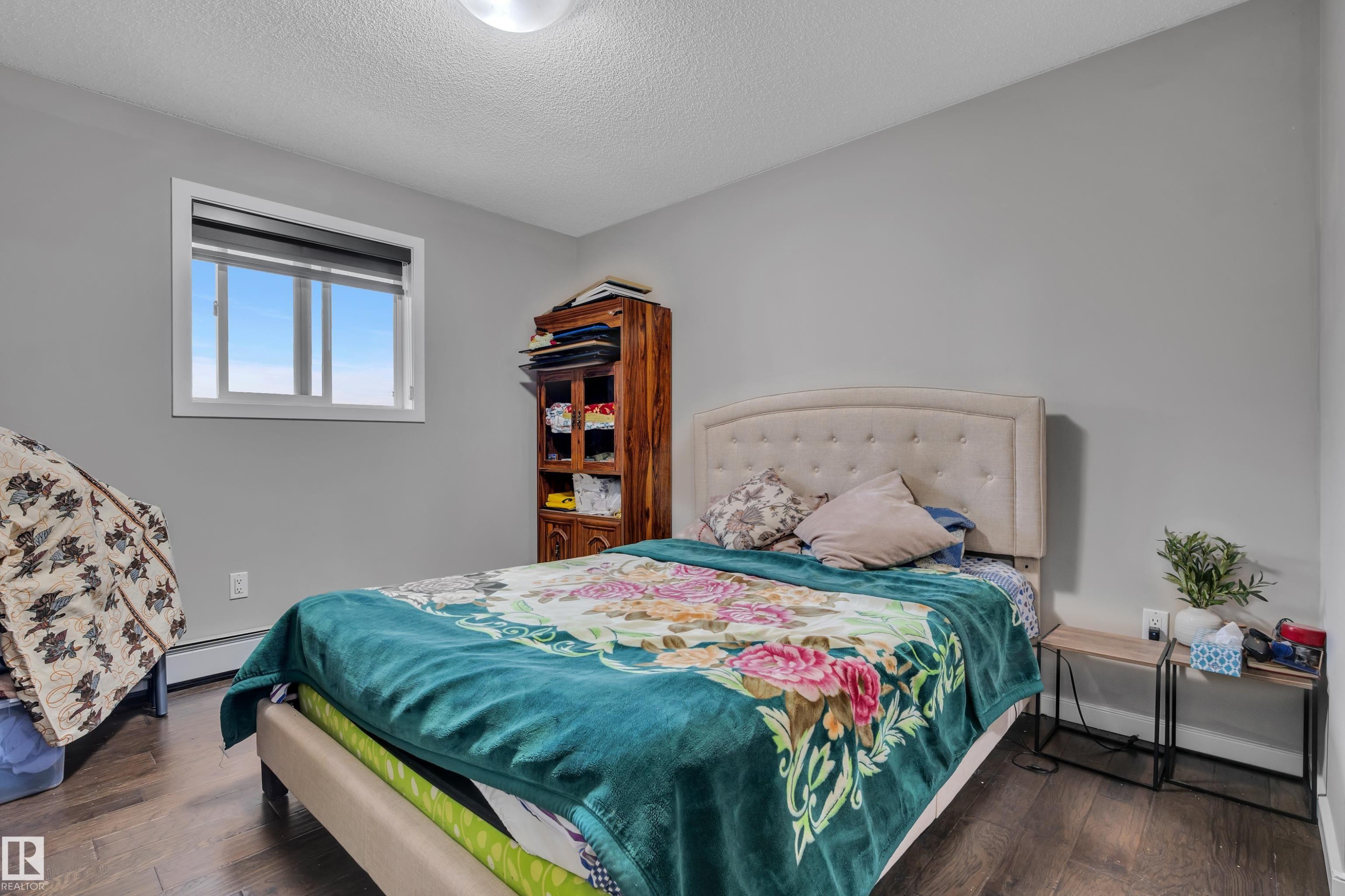This room features dark wood flooring and light gray walls - 320 392 Silver Berry Road, Edmonton, AB - Indoor Photo Showing Bedroom