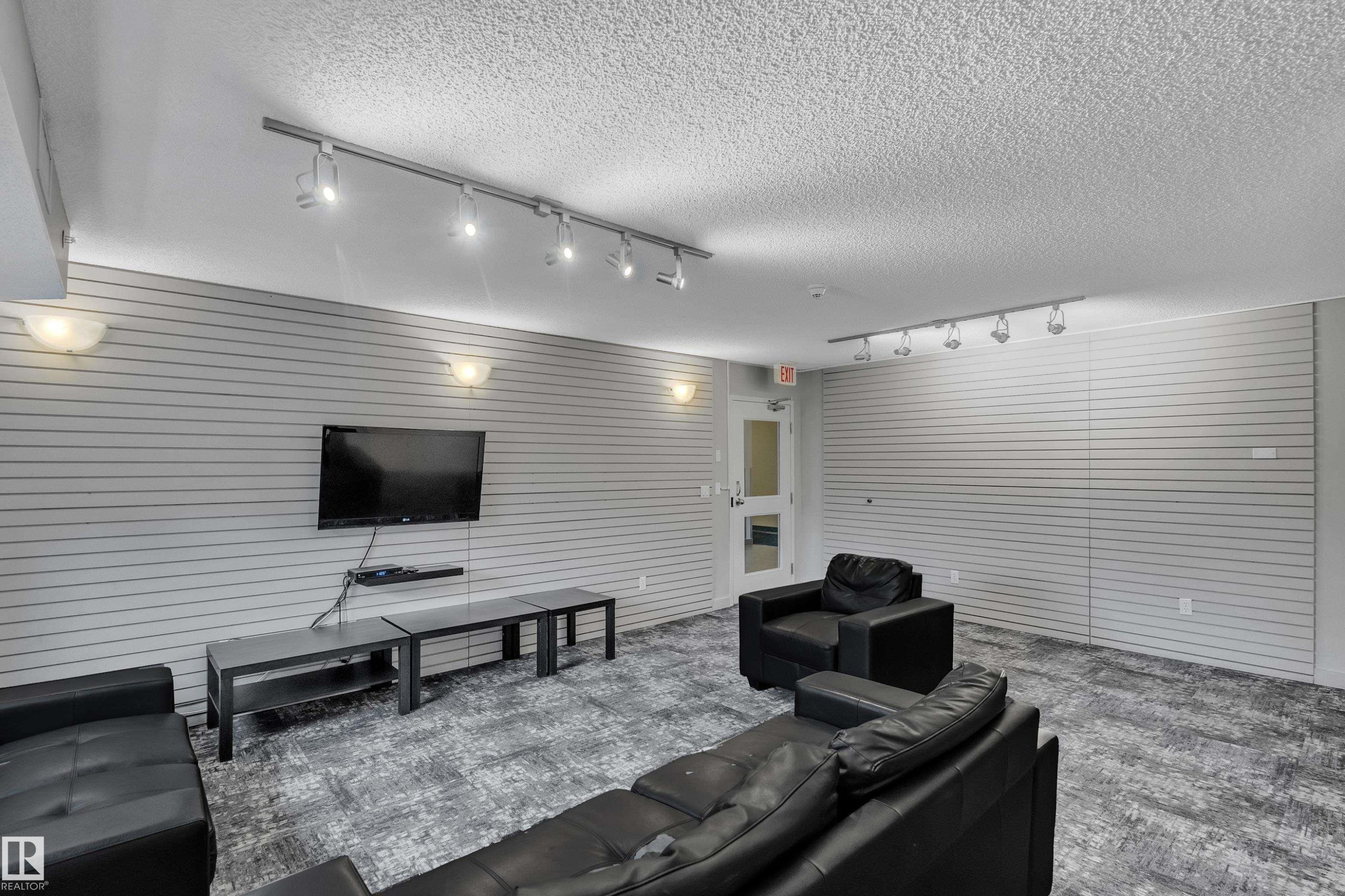 This versatile space features track lighting, sconces, and a wall-mounted television, creating an inviting atmosphere - 320 392 Silver Berry Road, Edmonton, AB - Indoor Photo Showing Living Room