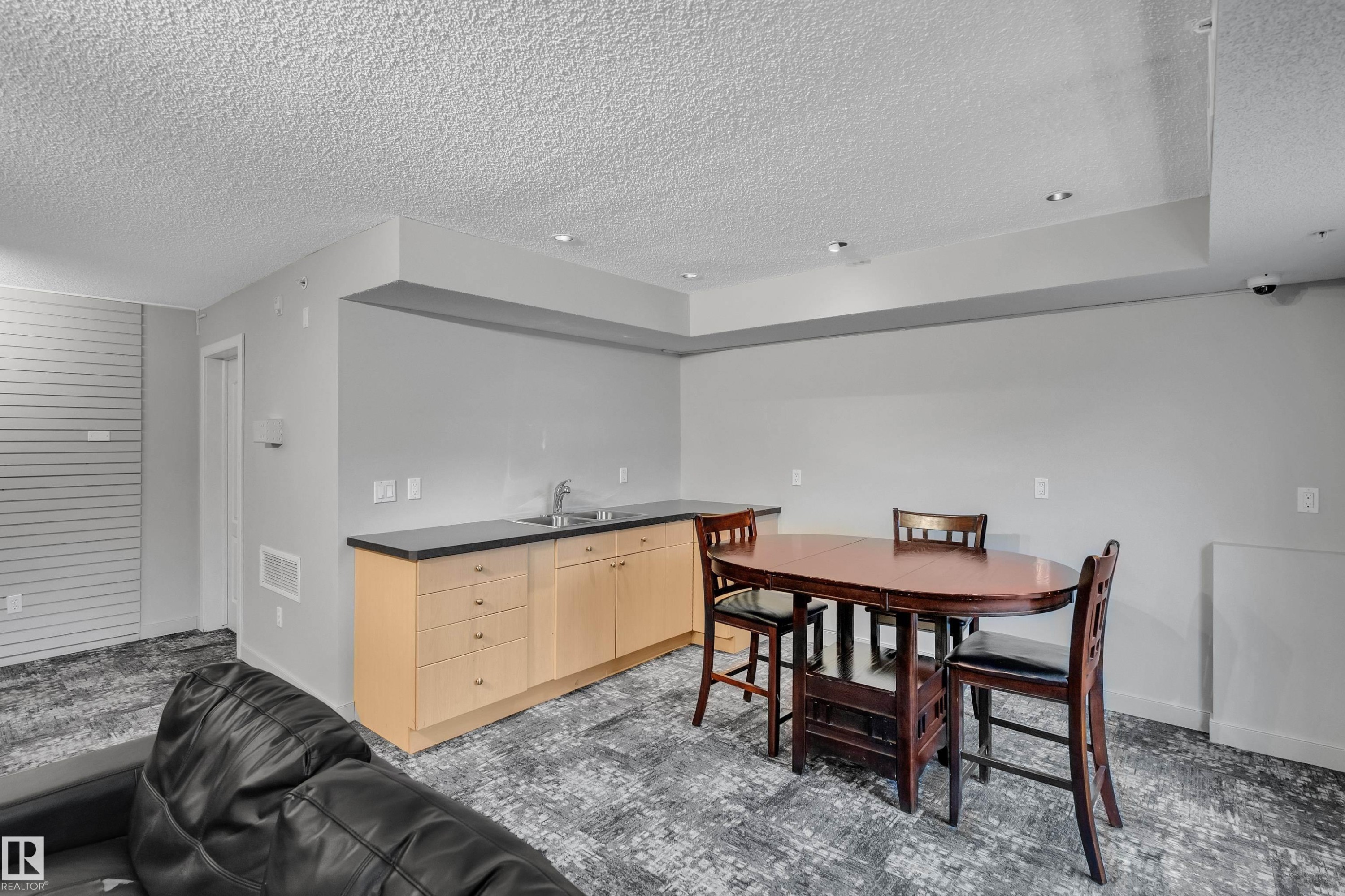 This versatile space features light-toned cabinetry with a sink and dark countertops, recessed lighting, and patterned carpeting - 320 392 Silver Berry Road, Edmonton, AB - Indoor Photo Showing Dining Room