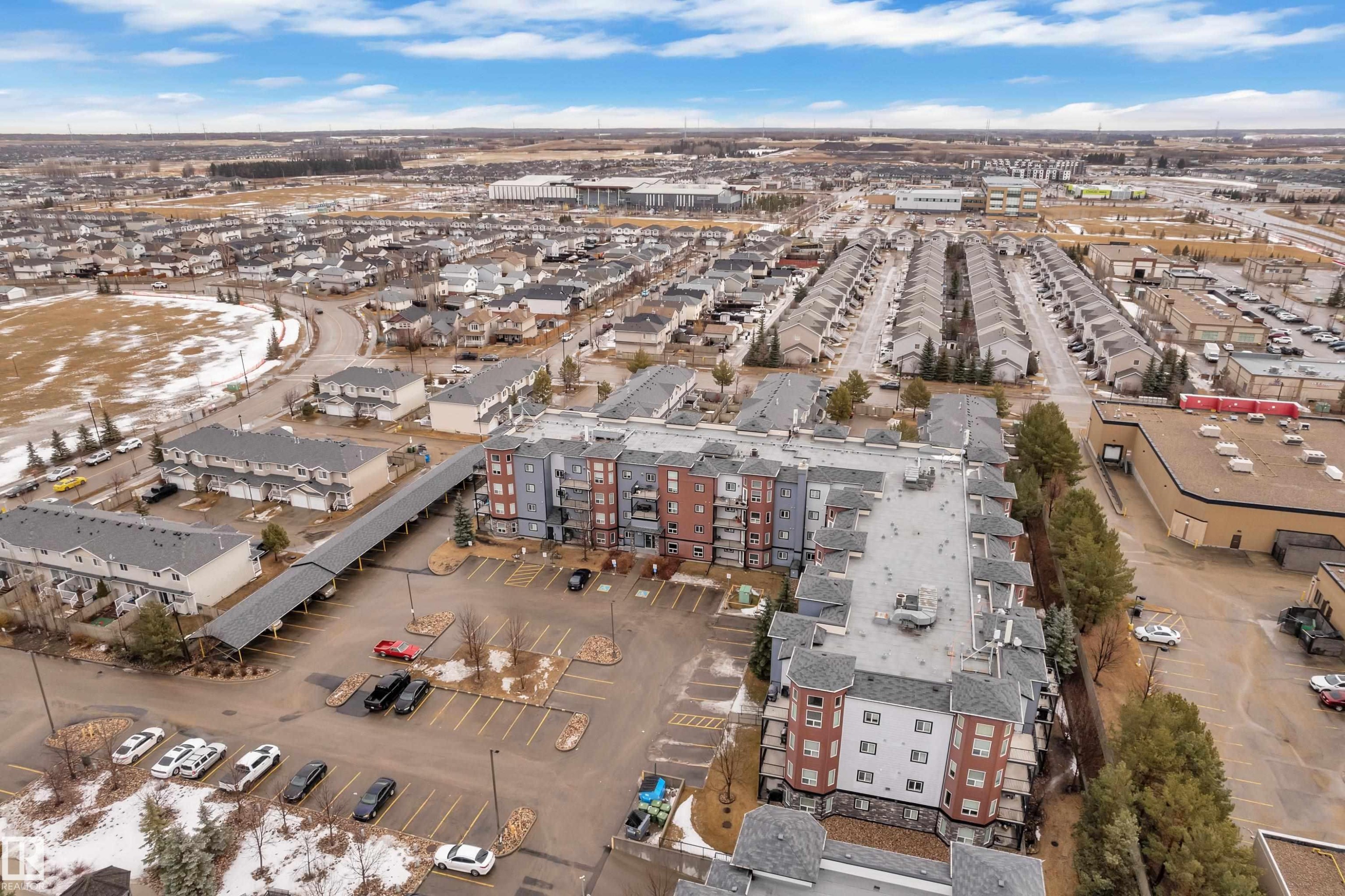 This property features a multi-story building with a distinctive facade, surrounded by paved parking areas - 320 392 Silver Berry Road, Edmonton, AB - Outdoor With View