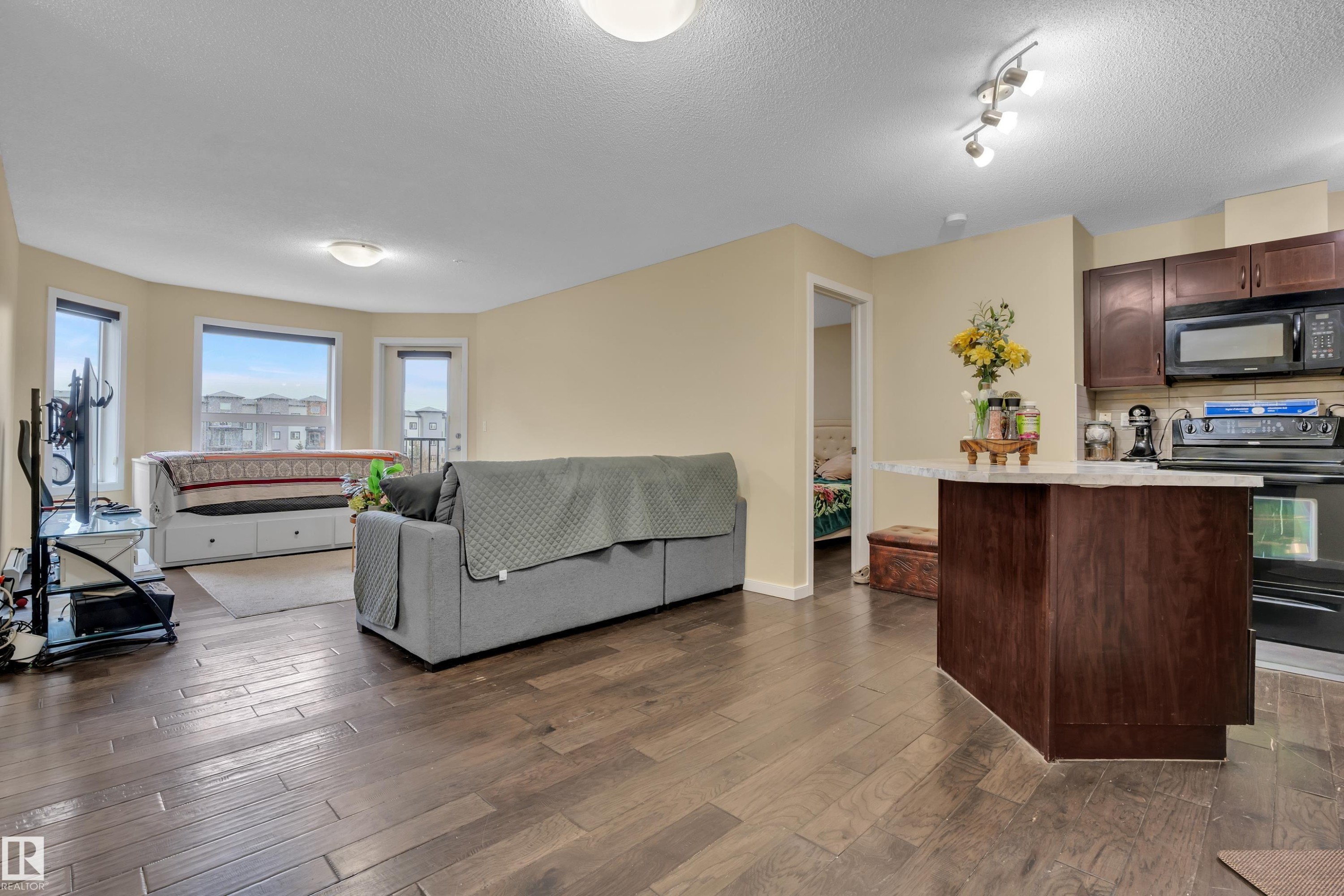 The living area features hardwood floors and large bay windows offering views of the surrounding neighborhood - 320 392 Silver Berry Road, Edmonton, AB - Indoor