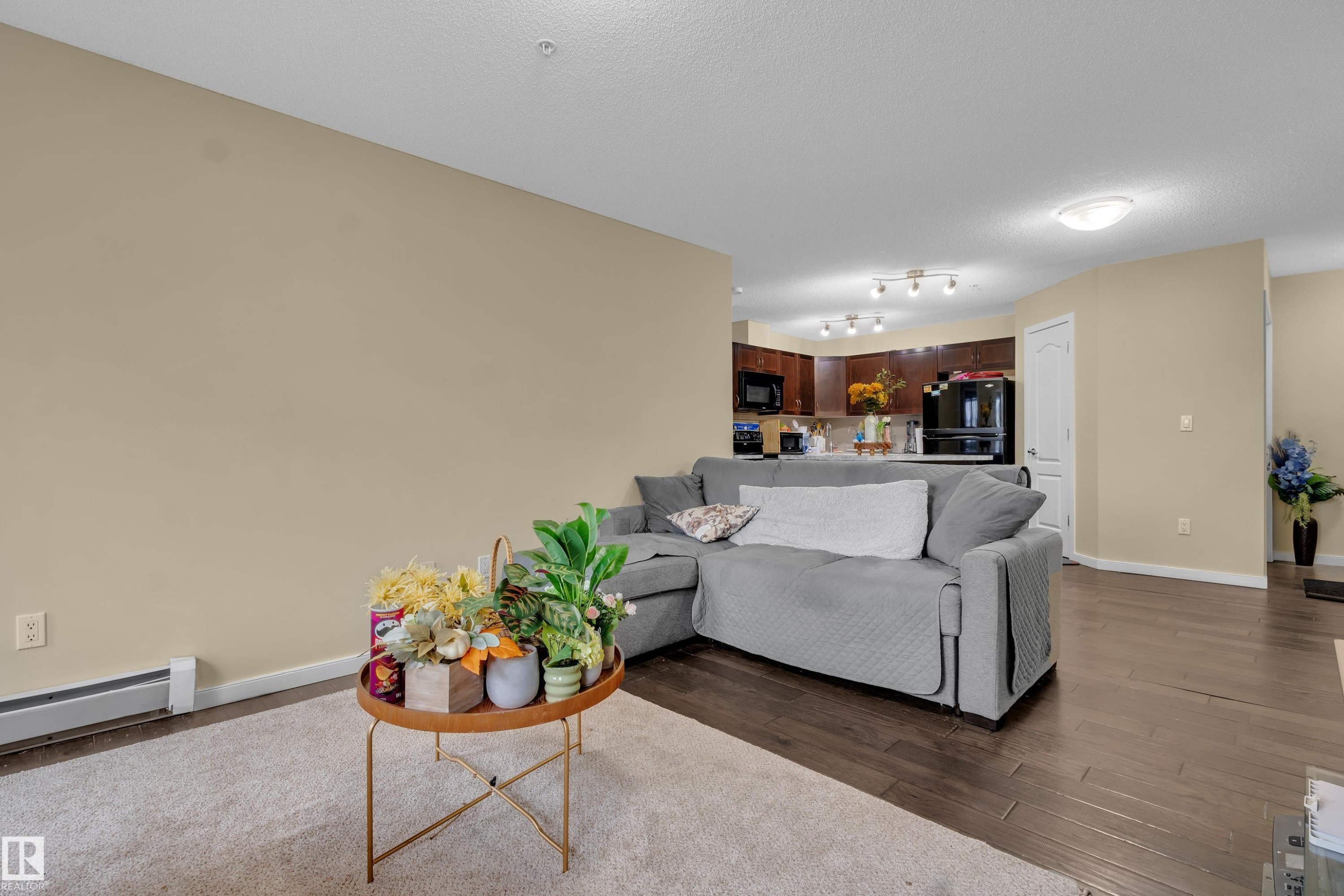 This living area features rich dark hardwood floors and light neutral walls, creating a bright and inviting atmosphere - 320 392 Silver Berry Road, Edmonton, AB - Indoor Photo Showing Living Room