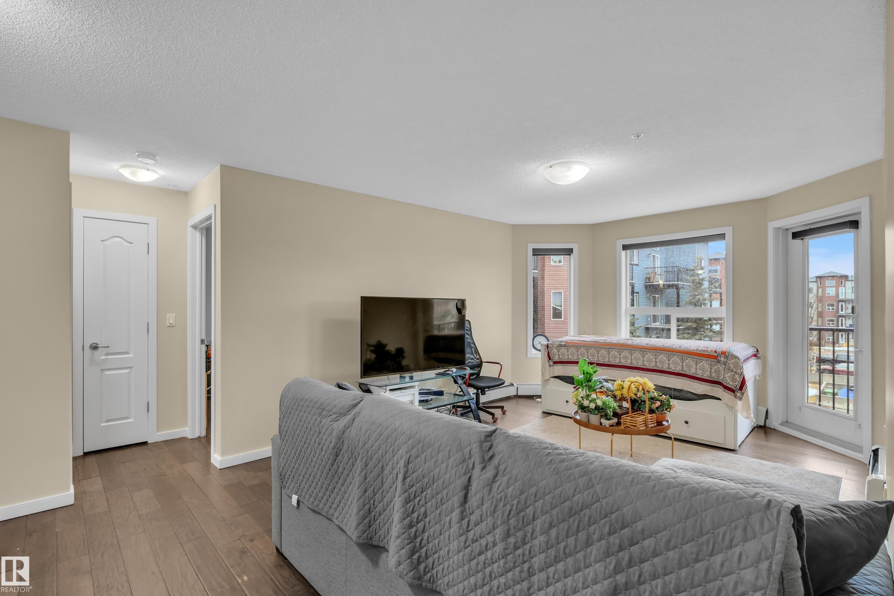 The living space features hardwood floors, light-colored walls, and large windows that provide natural light - 320 392 Silver Berry Road, Edmonton, AB - Indoor Photo Showing Living Room