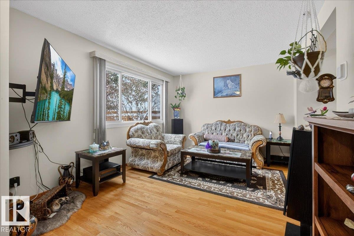 Living area featuring hardwood flooring, a large window providing natural light, and a textured ceiling - 2 Mcleod Place, Edmonton, AB - Indoor Photo Showing Living Room