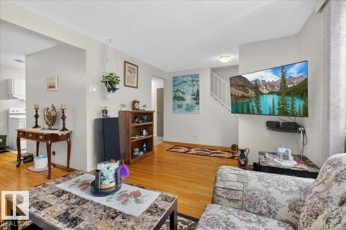 The living area features hardwood flooring, light grey walls, and a staircase with white railings - 2 Mcleod Place, Edmonton, AB - Indoor Photo Showing Living Room