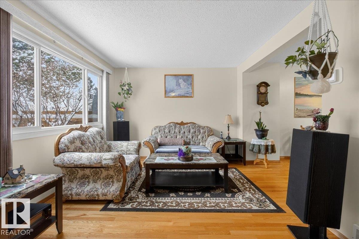 Living area featuring hardwood flooring, light-colored walls, and a large window providing natural light - 2 Mcleod Place, Edmonton, AB - Indoor Photo Showing Living Room