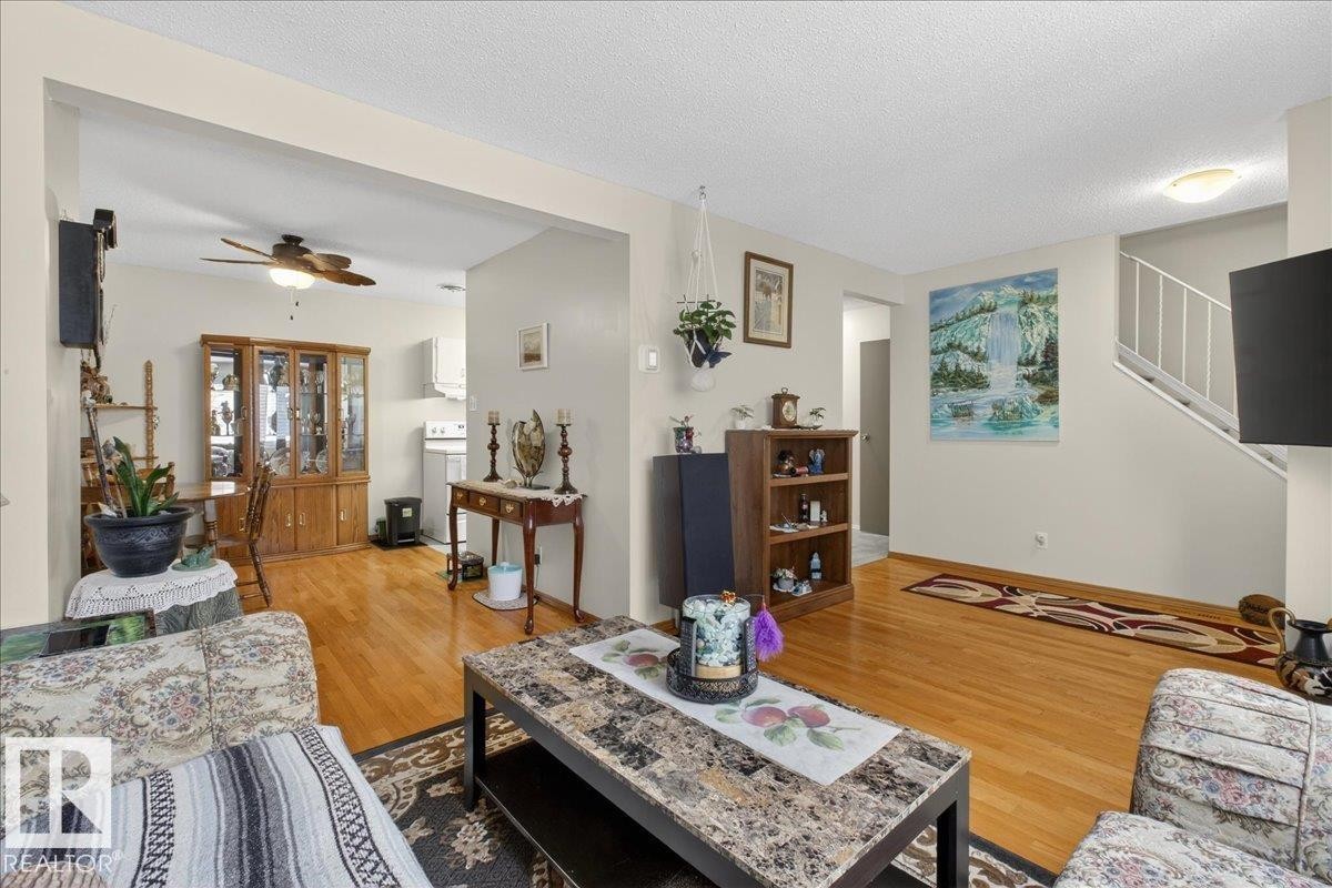 The property features an open living area with hardwood flooring, light-colored walls, and a ceiling fan in the dining space - 2 Mcleod Place, Edmonton, AB - Indoor Photo Showing Living Room