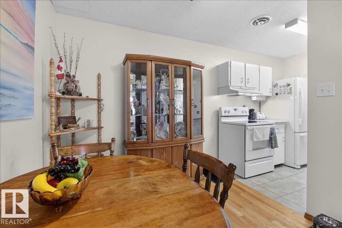 The property features a kitchen area with white appliances and cabinetry, tiled flooring, and a window for natural light - 2 Mcleod Place, Edmonton, AB - Indoor Photo Showing Other Room