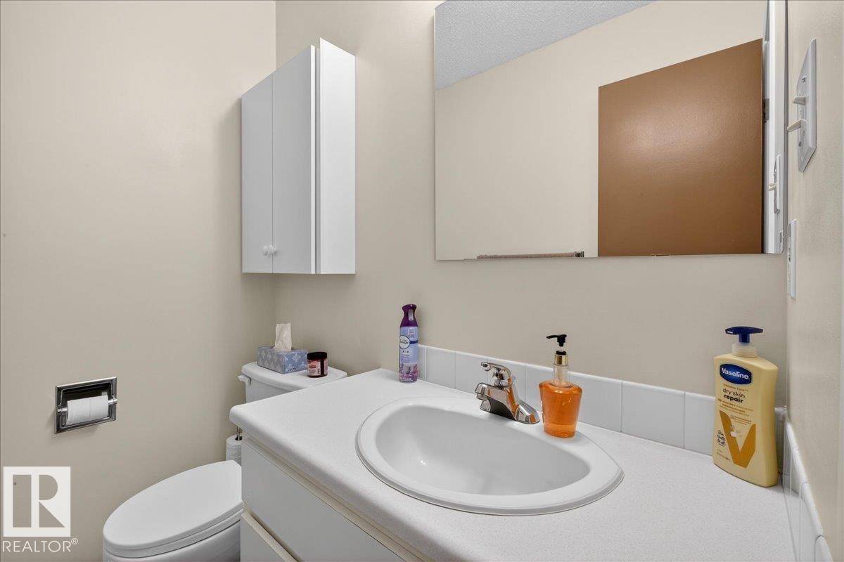 Bathroom featuring a white vanity with an integrated sink, a wall-mounted medicine cabinet, and a mirror - 2 Mcleod Place, Edmonton, AB - Indoor Photo Showing Bathroom