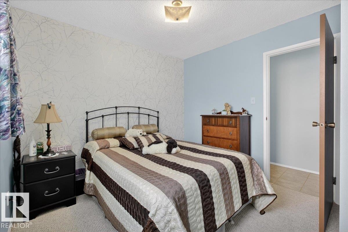 This bedroom features a light blue painted wall and a patterned accent wall - 2 Mcleod Place, Edmonton, AB - Indoor Photo Showing Bedroom