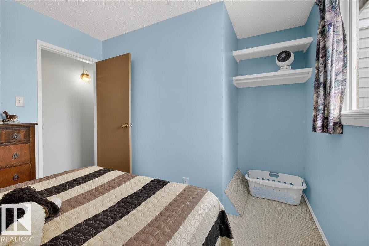 Bedroom with light blue walls, a window providing natural light, and a brown door - 2 Mcleod Place, Edmonton, AB - Indoor Photo Showing Bedroom