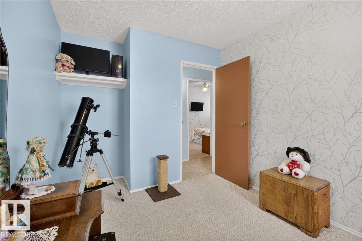 This room features light blue walls, a textured ceiling, and patterned wallpaper - 2 Mcleod Place, Edmonton, AB - Indoor Photo Showing Other Room