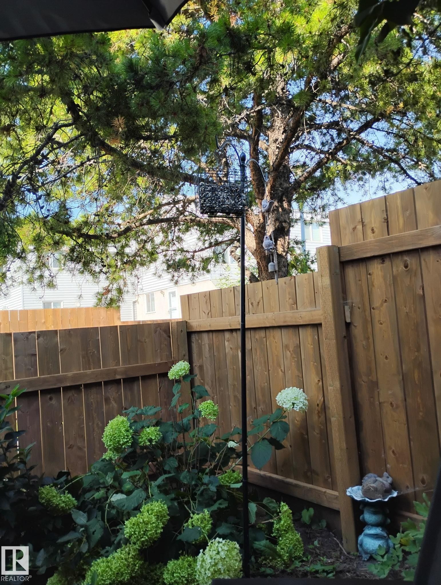 The property features a private yard with a wood fence, mature trees, and flowering shrubs - 2 Mcleod Place, Edmonton, AB - Outdoor
