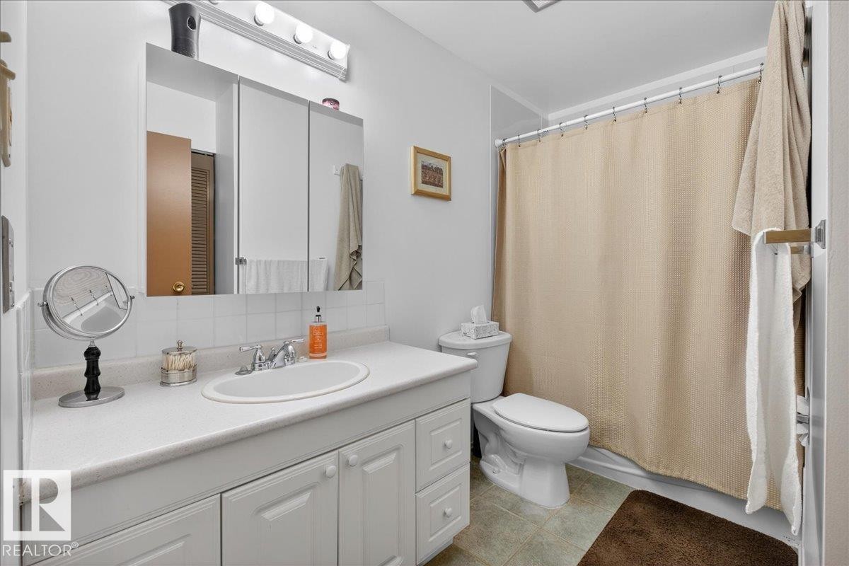 Bathroom featuring a vanity with a white countertop and an integrated sink, a wall-mounted medicine cabinet, and a shower with a shower curtain - 2 Mcleod Place, Edmonton, AB - Indoor Photo Showing Bathroom