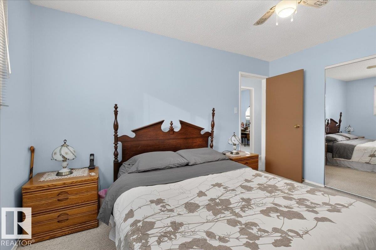 Bedroom featuring a ceiling fan, a window with blinds, and mirrored closet doors - 2 Mcleod Place, Edmonton, AB - Indoor Photo Showing Bedroom