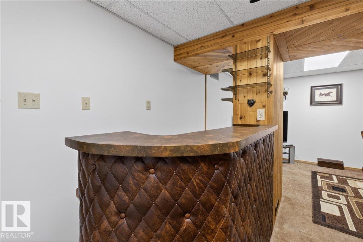 The property includes a bar area with a tufted, diamond-patterned facade and a countertop, complemented by a wooden support structure and shelves - 2 Mcleod Place, Edmonton, AB - Indoor