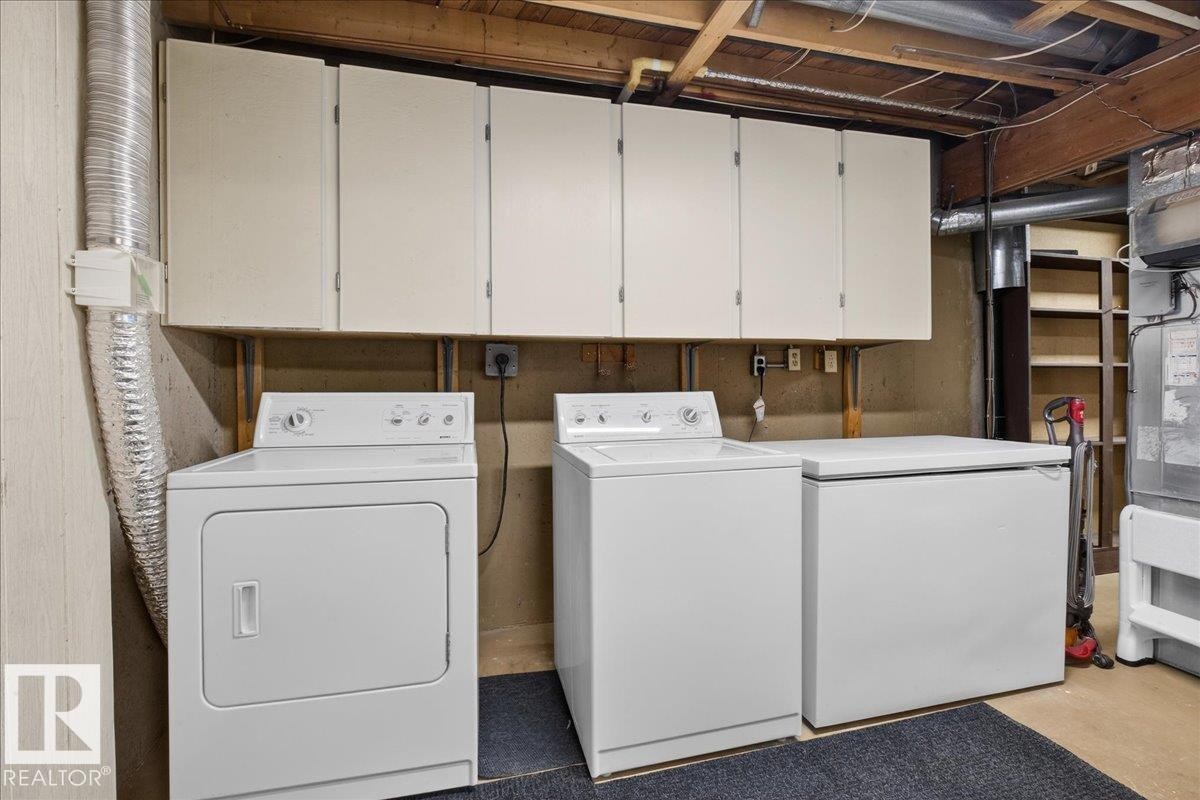 The property includes a dedicated laundry area with a washer, dryer, and overhead white cabinetry - 2 Mcleod Place, Edmonton, AB - Indoor Photo Showing Laundry Room