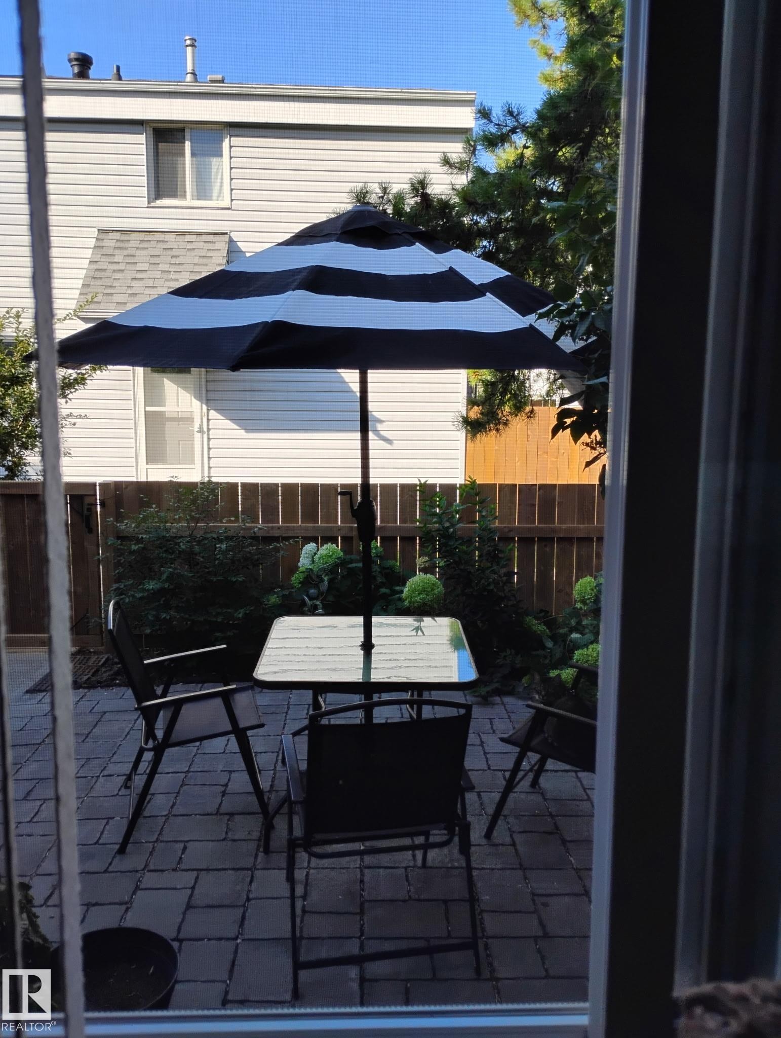 The property includes a paved patio area, featuring a striped umbrella for shade - 2 Mcleod Place, Edmonton, AB - Outdoor With Deck Patio Veranda