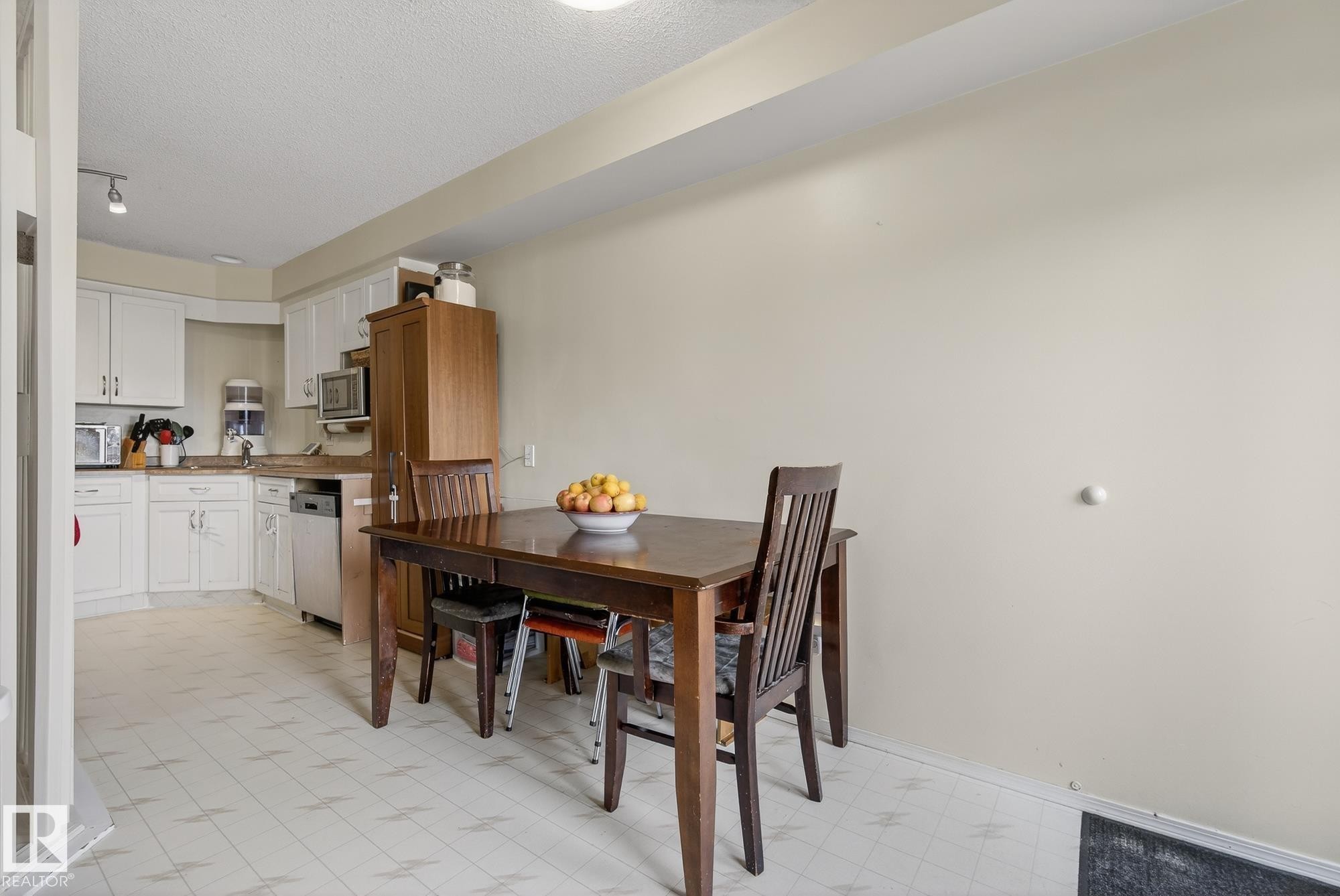 The kitchen and dining area features white cabinetry, stainless steel appliances, and a tiled floor - 2006 Mill Woods Road E, Edmonton, AB - Indoor