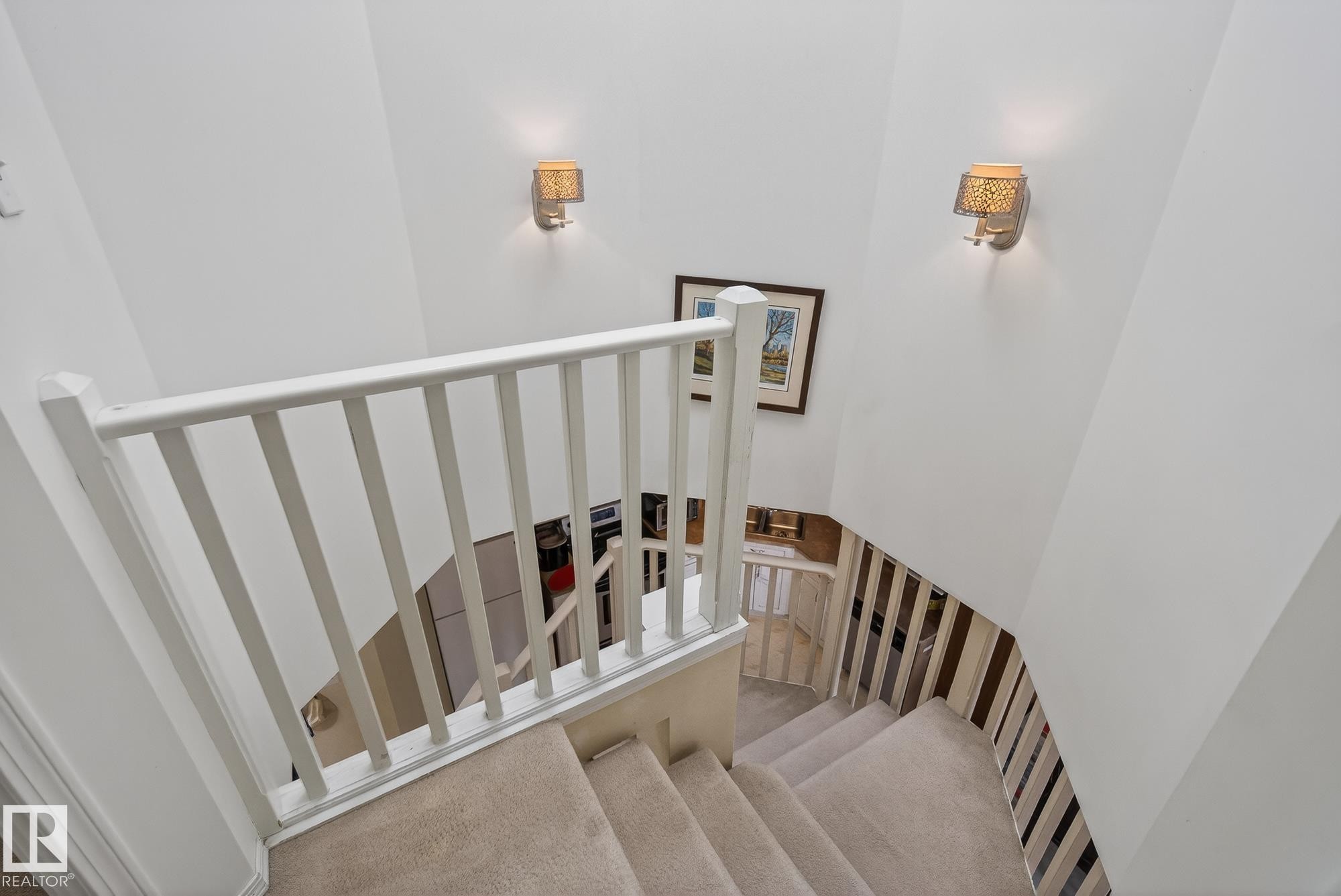 Carpeted staircase with white balusters and railings, illuminated by two wall sconces - 2006 Mill Woods Road E, Edmonton, AB - Indoor Photo Showing Other Room