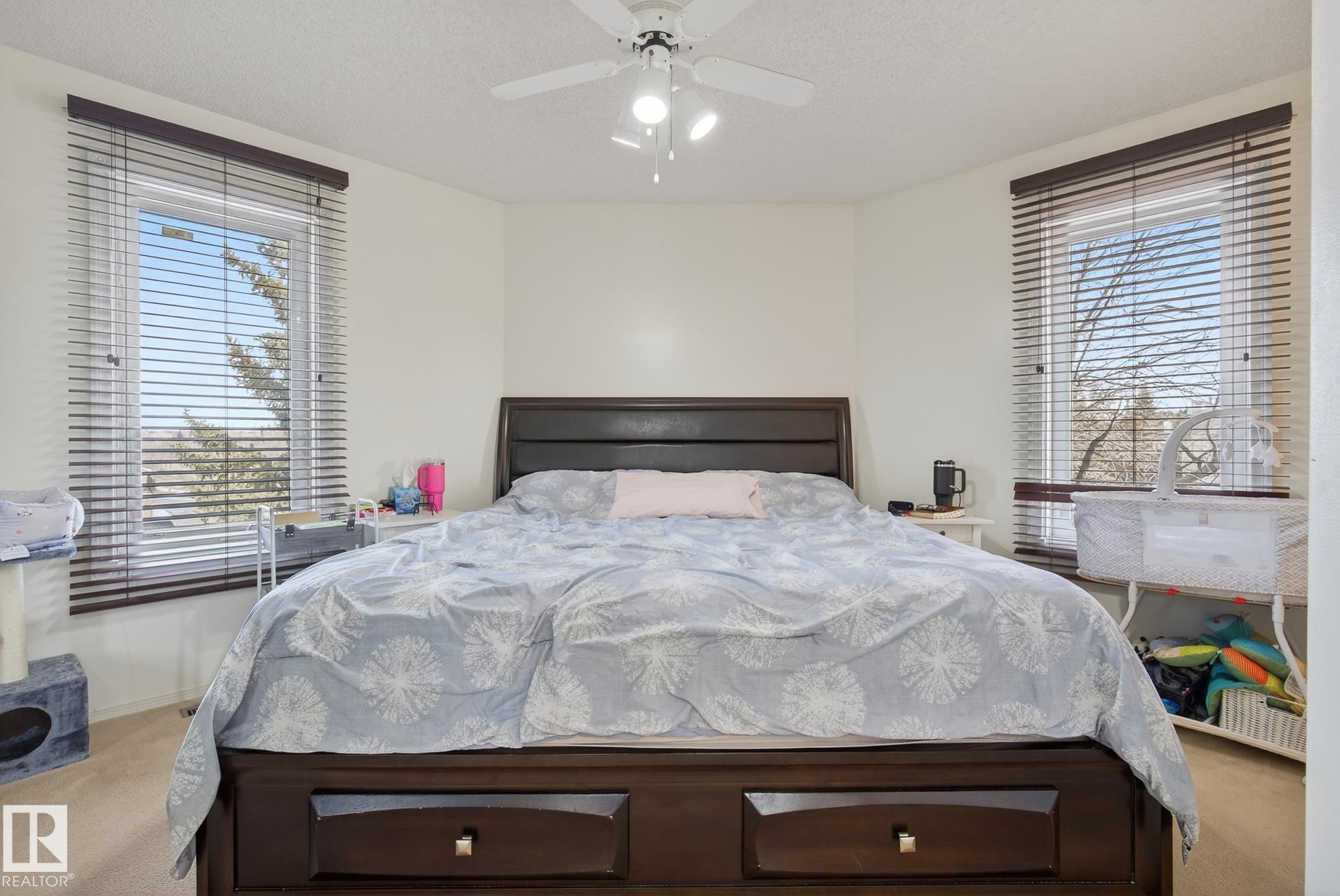 This room features a dark wood bed frame with storage drawers, light-colored carpeting, and a ceiling fan with integrated lighting - 2006 Mill Woods Road E, Edmonton, AB - Indoor Photo Showing Bedroom